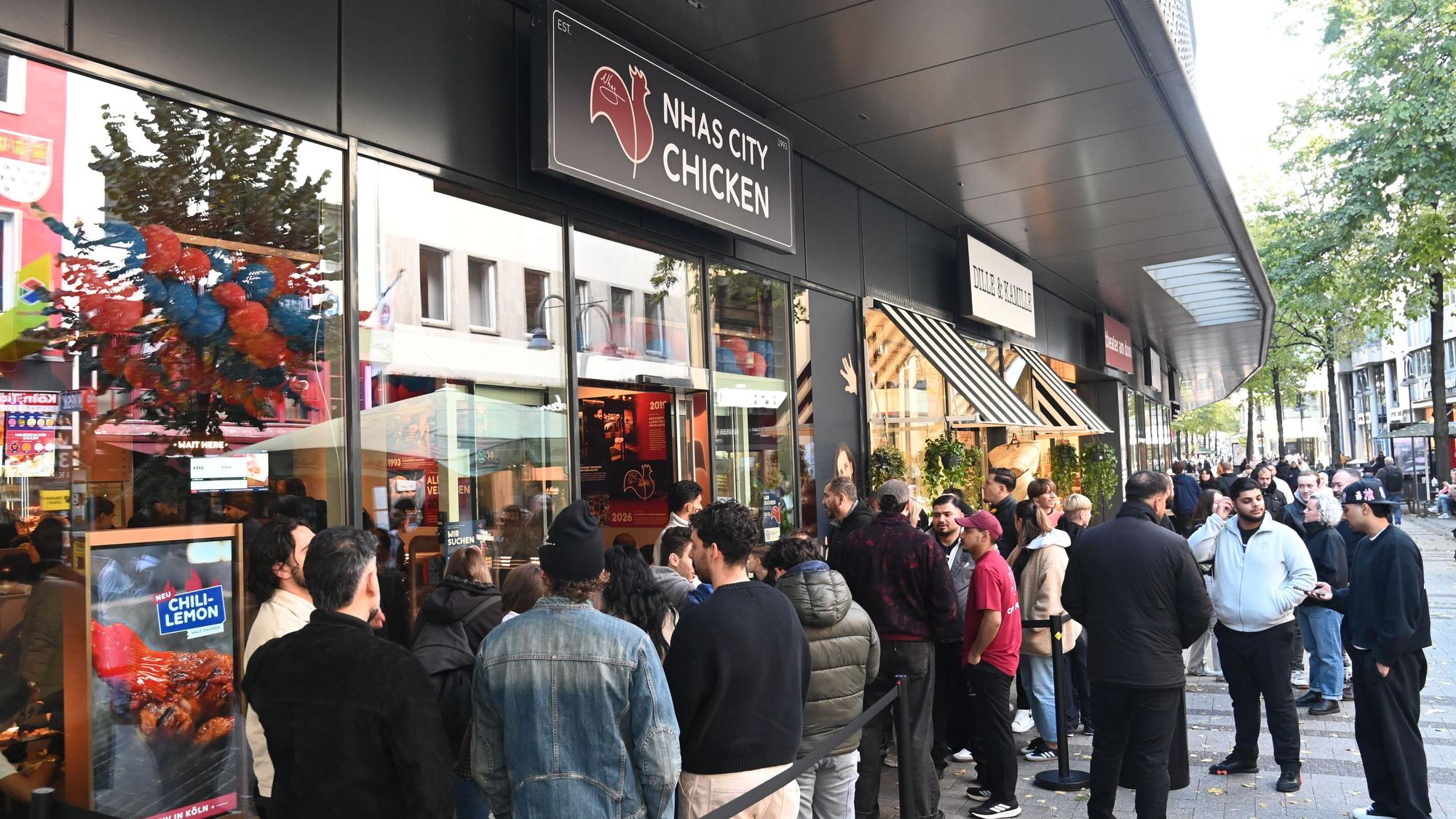 Menschen stehen vor dem Fast-Food-Imbiss Nhas City Chicken an der Breite Straße.