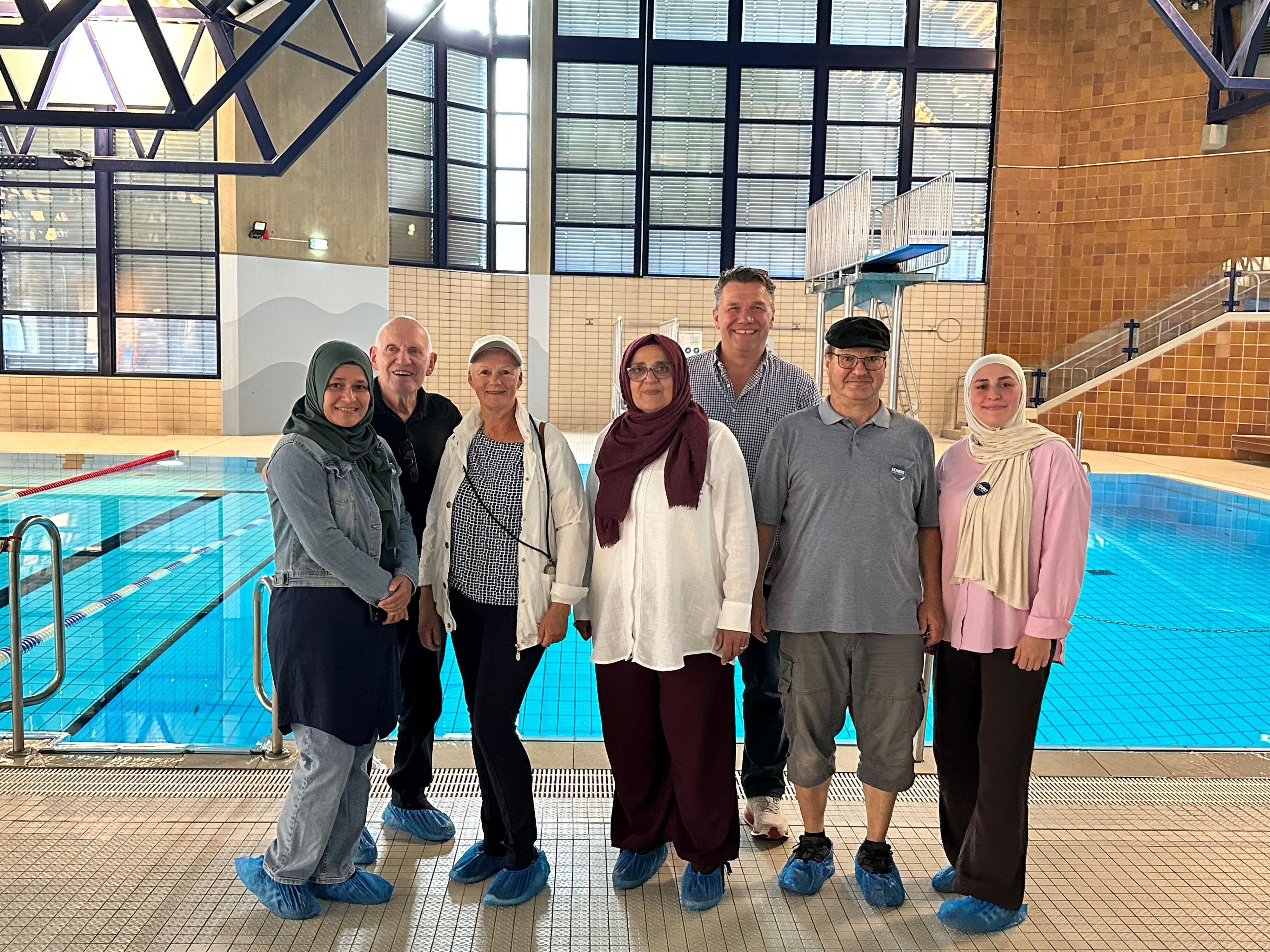 Aktivistinnen für und Unterstützer:innen des Frauenschwimmens stehen am Rand eines Schwimmbeckens.