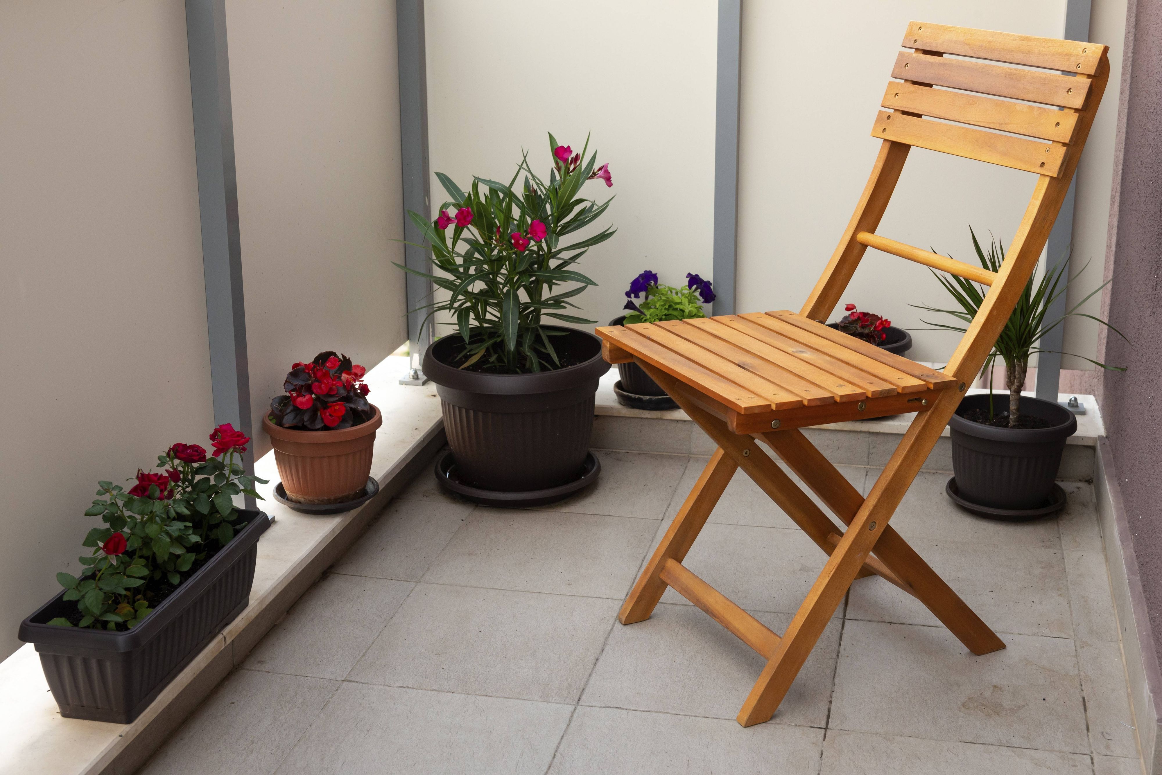 Holzstuhl und Topfpflanzen auf einem Balkon