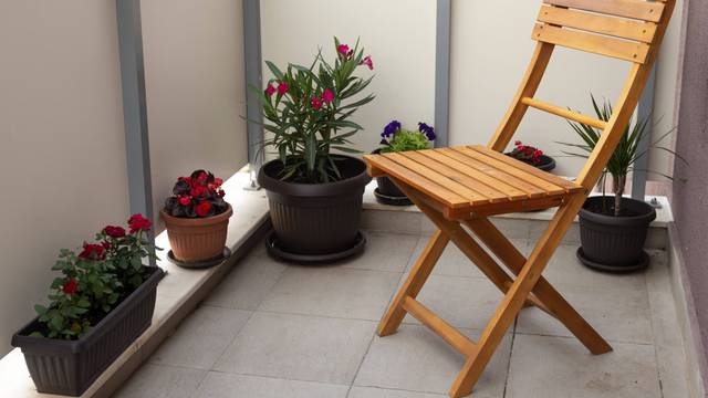 Holzstuhl und Topfpflanzen auf einem Balkon