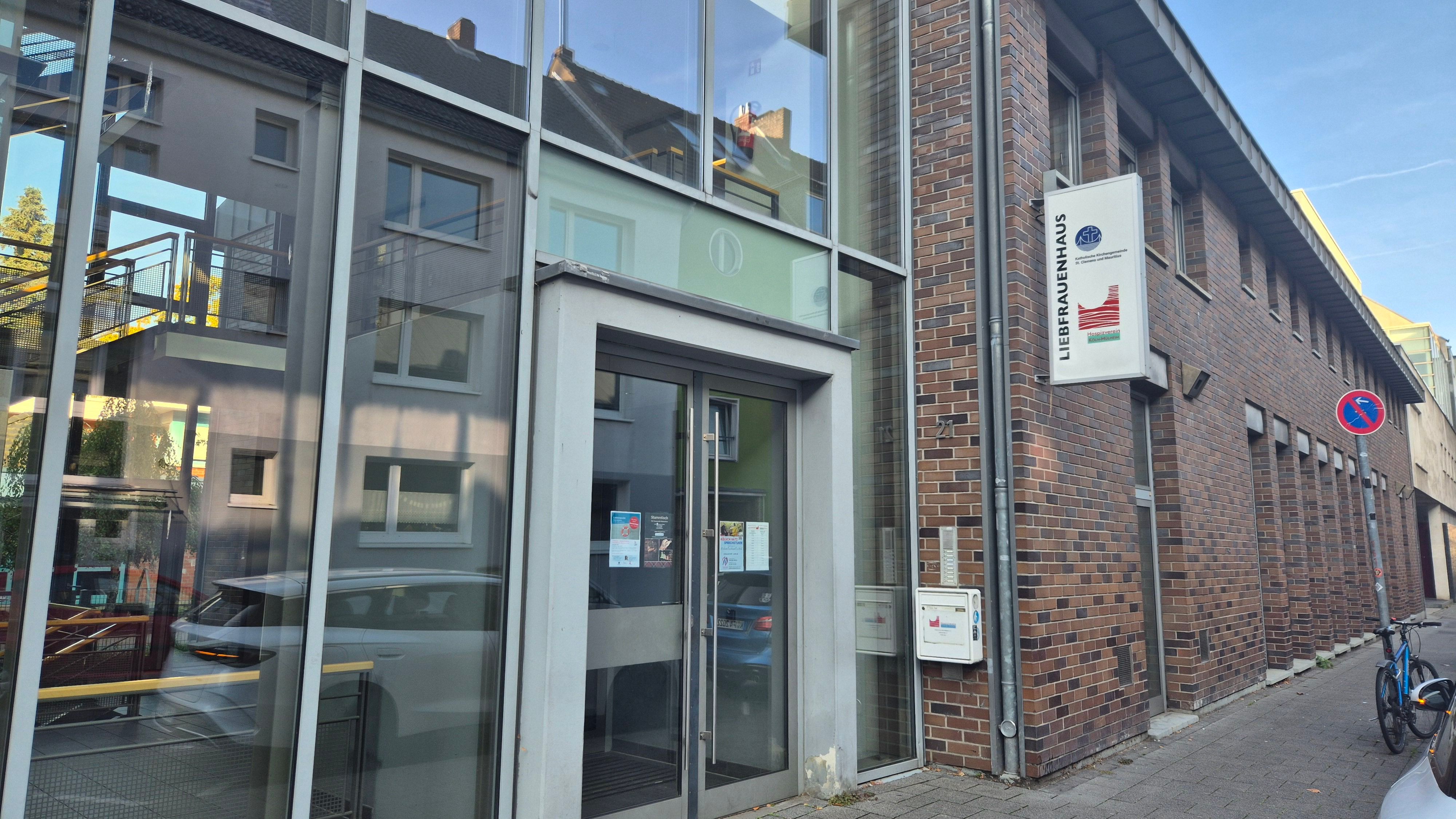 Der Eingang eines Backsteingebäudes mit Glasfront und einem Schild „Liebfrauenhaus“ an einer Straße