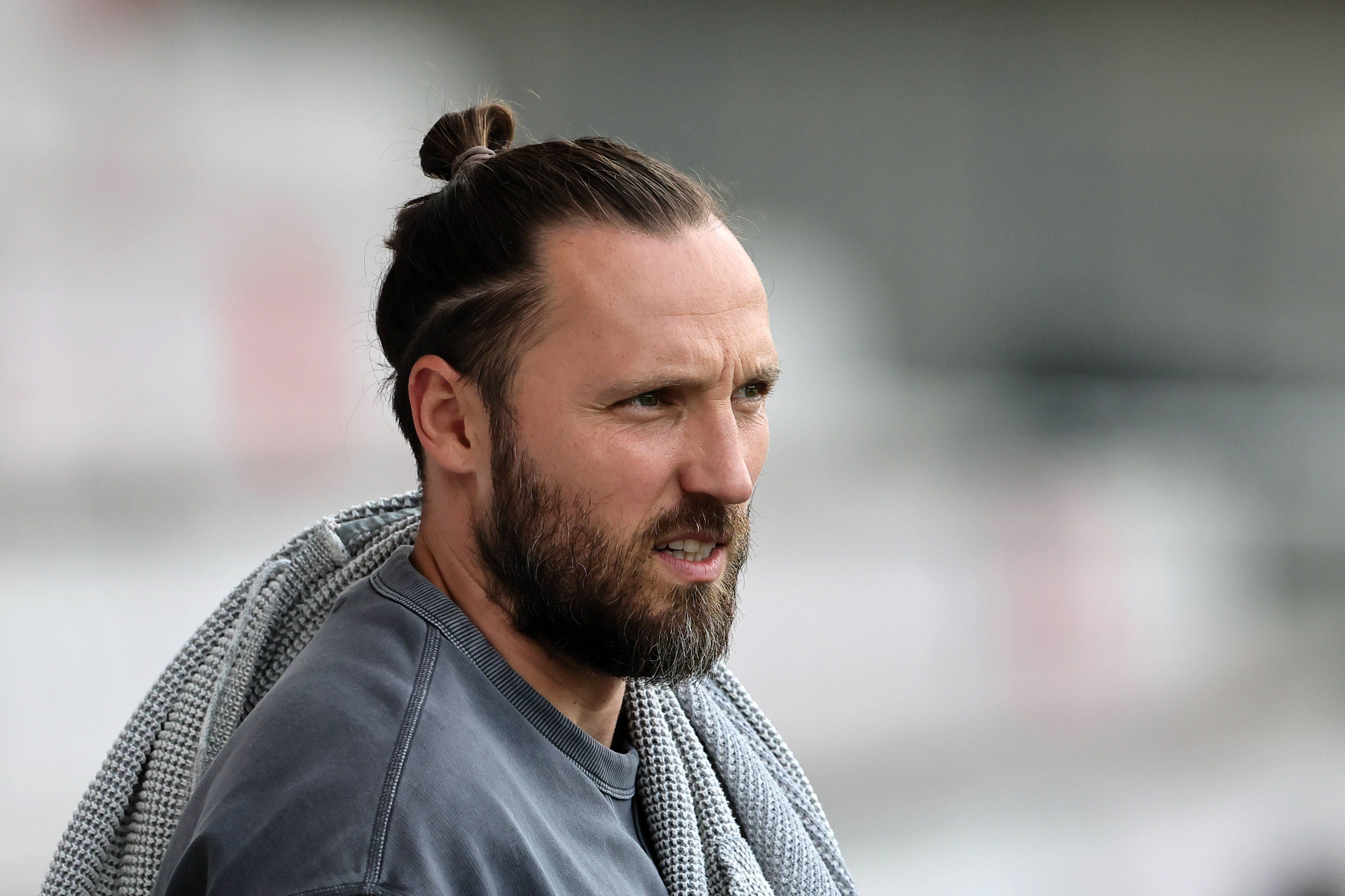 Marco Höger steht in Zivil am Spielfeldrand.