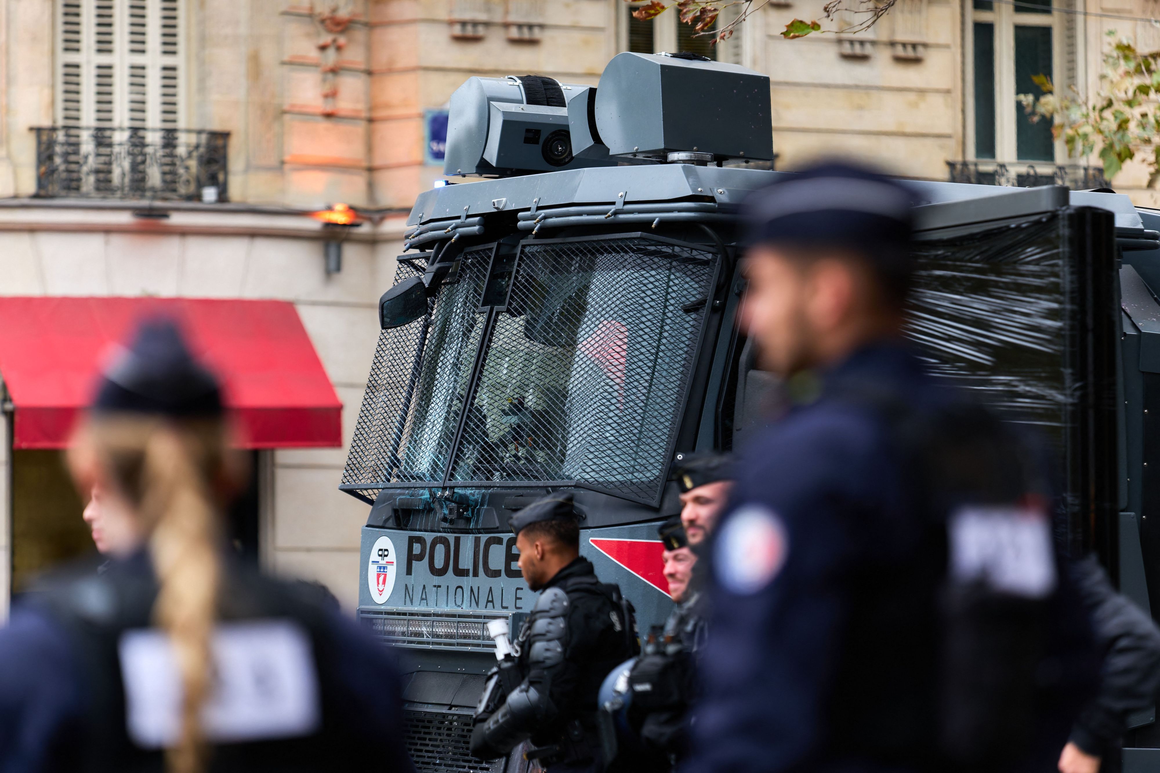 Polizisten in Schutzausrüstung stehen am Samstag vor einem Wasserwerfer der französischen „Police Nationale“ mit vergitterter Frontscheibe in Paris.