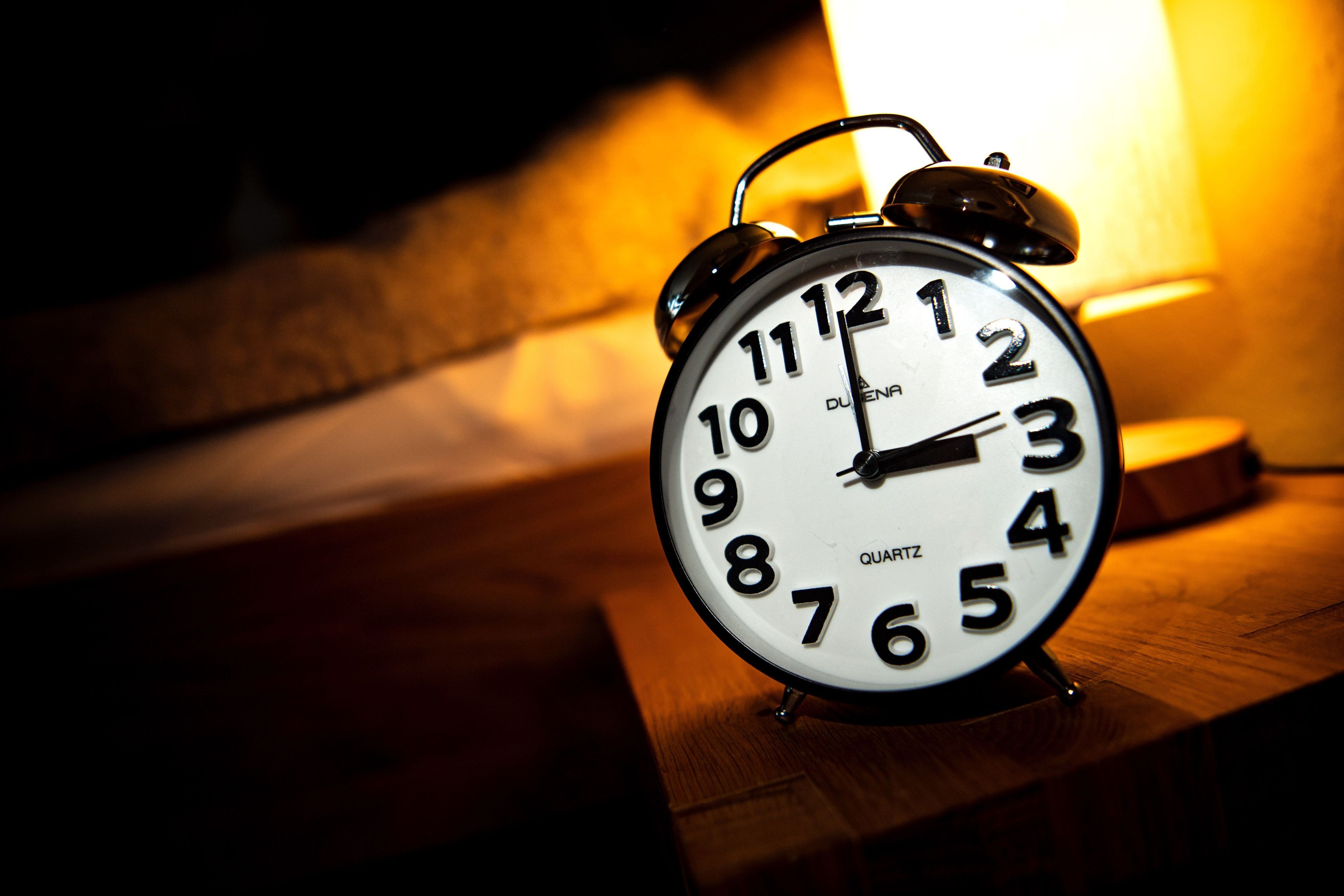 Eine Uhr steht neben einem Bett. Am letzten Sonntag im Oktober beginnt die sogenannte Winterzeit. (Archivbild)