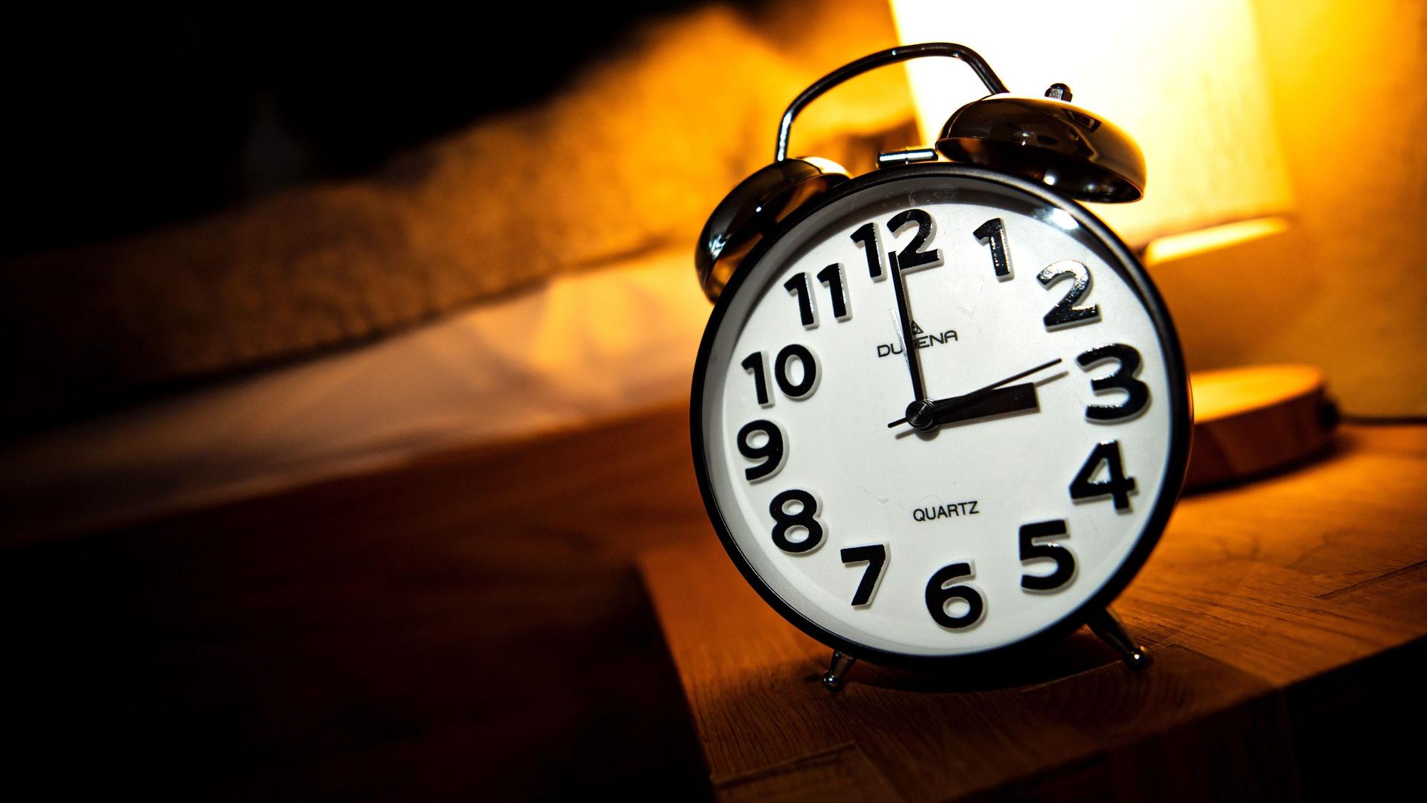 Eine Uhr steht neben einem Bett. Am letzten Sonntag im Oktober beginnt die sogenannte Winterzeit. (Archivbild)