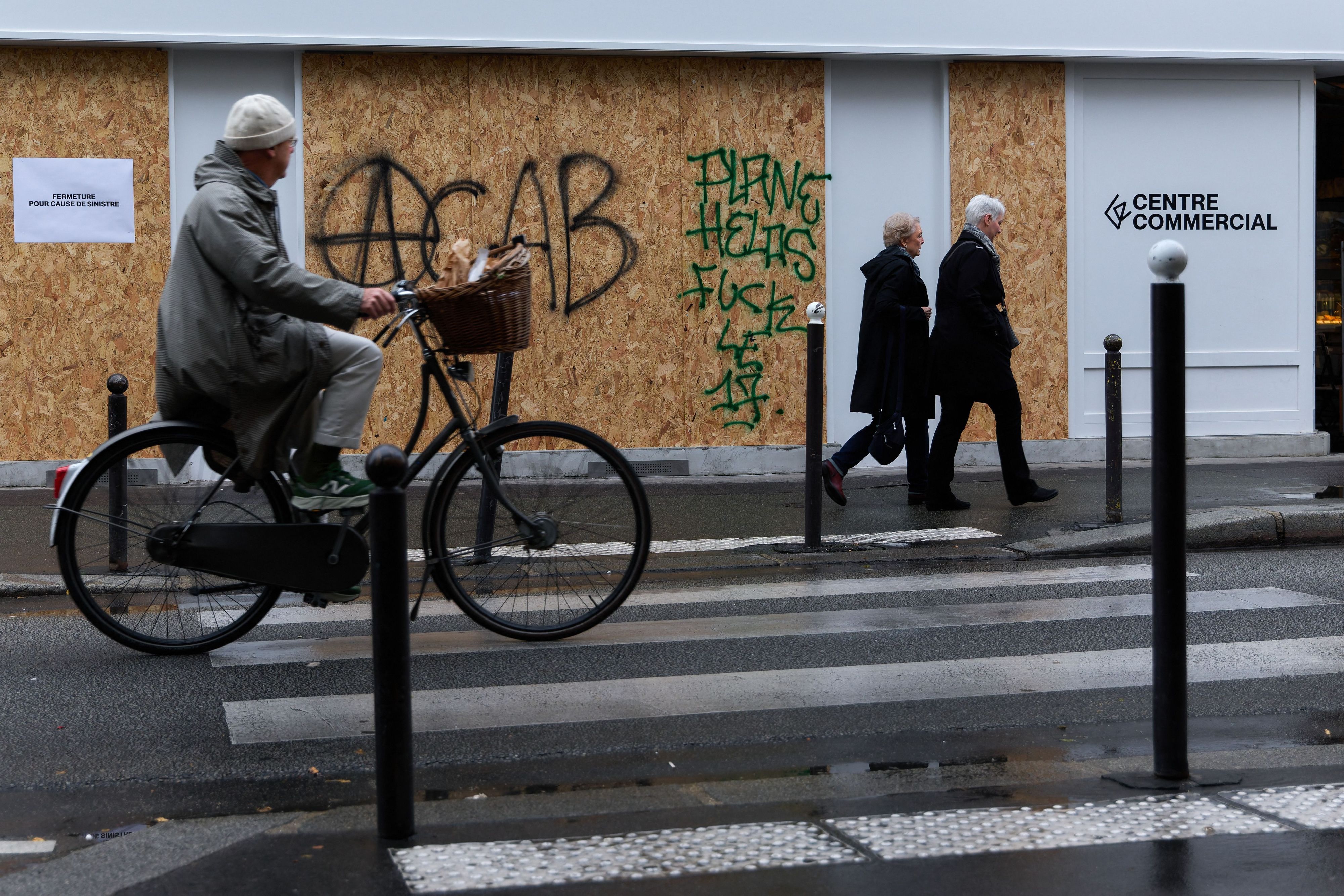 Ein Geschäft in Paris ist mit Brettern verkleidet, auf denen der Graffiti-Schriftzug „ACAB“ zu lesen ist.