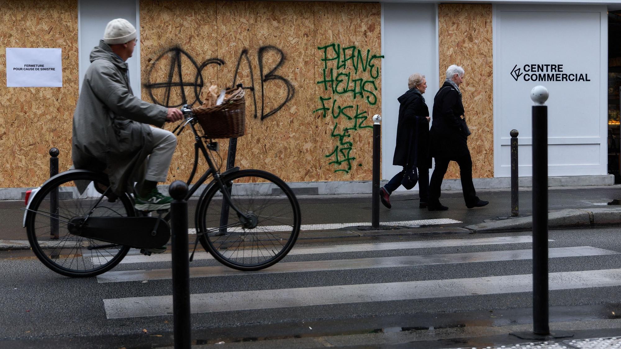 Ein Geschäft in Paris ist mit Brettern verkleidet, auf denen der Graffiti-Schriftzug „ACAB“ zu lesen ist.
