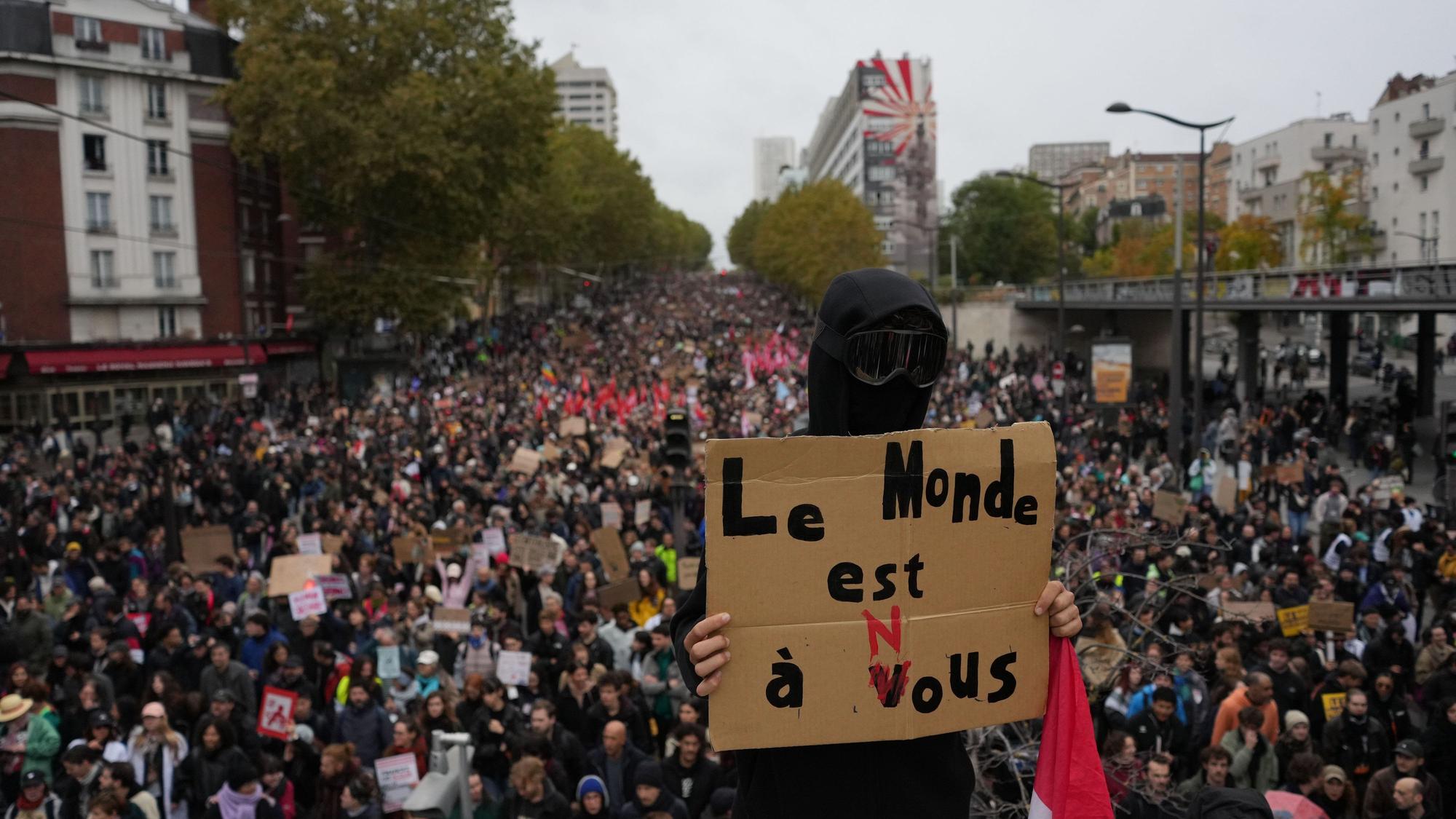 Ein Demonstrant hält in Paris ein Schild mit der Aufschrift „Die Welt gehört uns“ hoch.