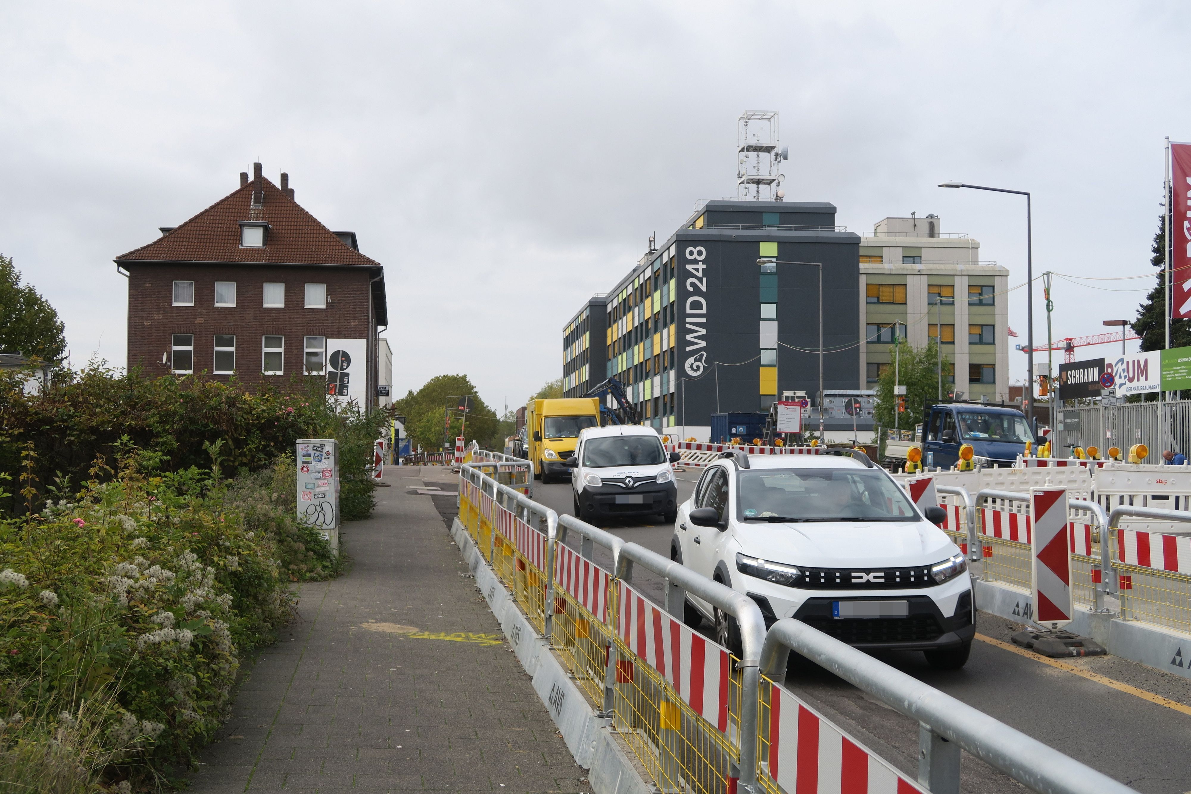 Autos fahren über eine durch Baustellen-Absperrungen verengte Straße.