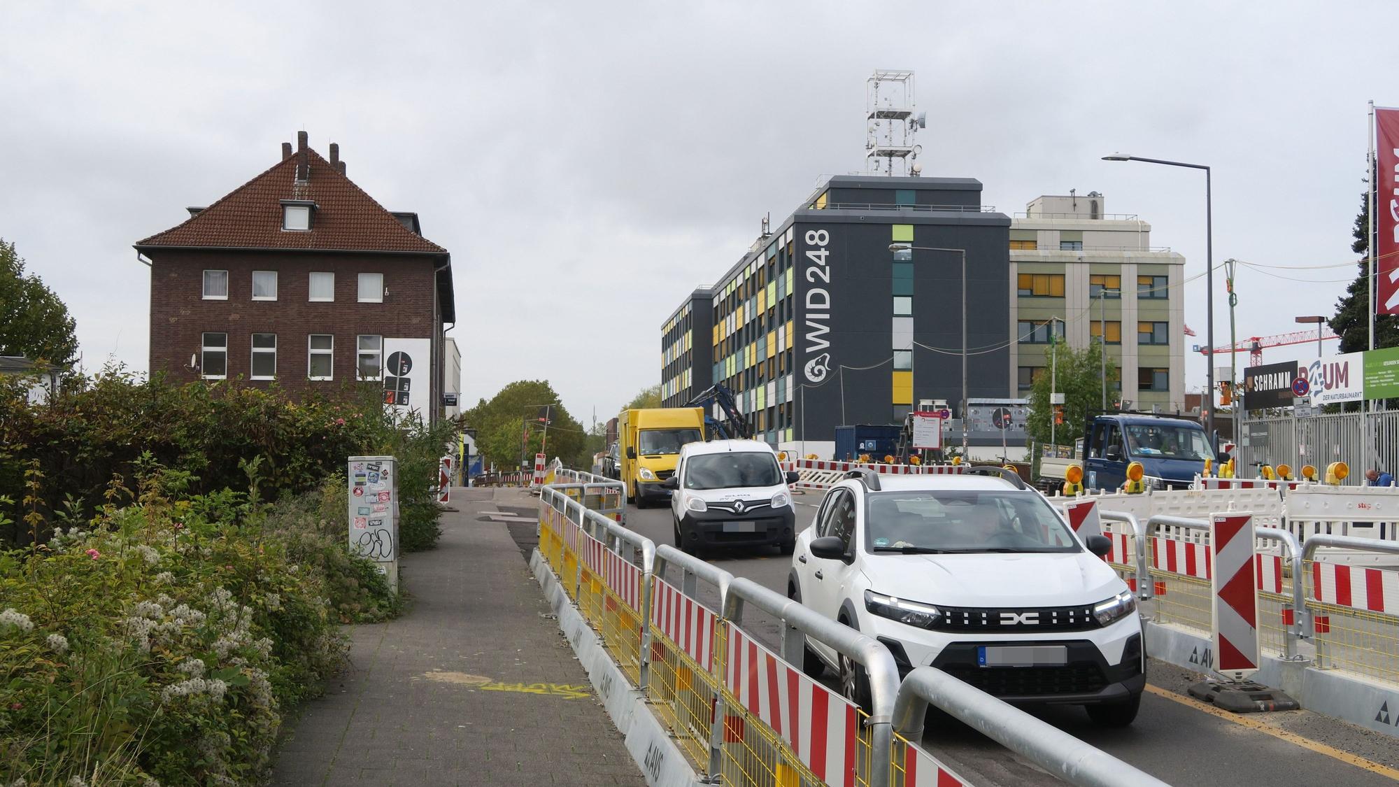 Autos fahren über eine durch Baustellen-Absperrungen verengte Straße.
