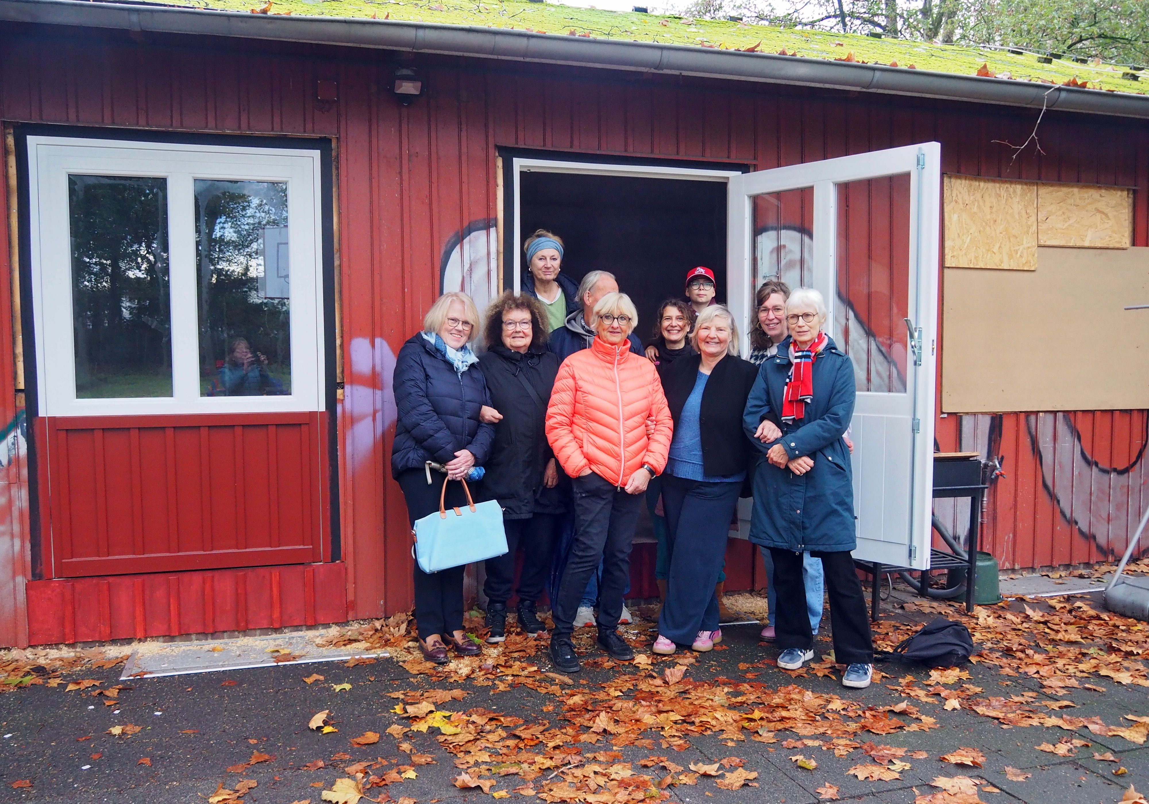 Eine Gruppe Frauen und ein Kind stehen in der Tür eines roten Gebäudes.
