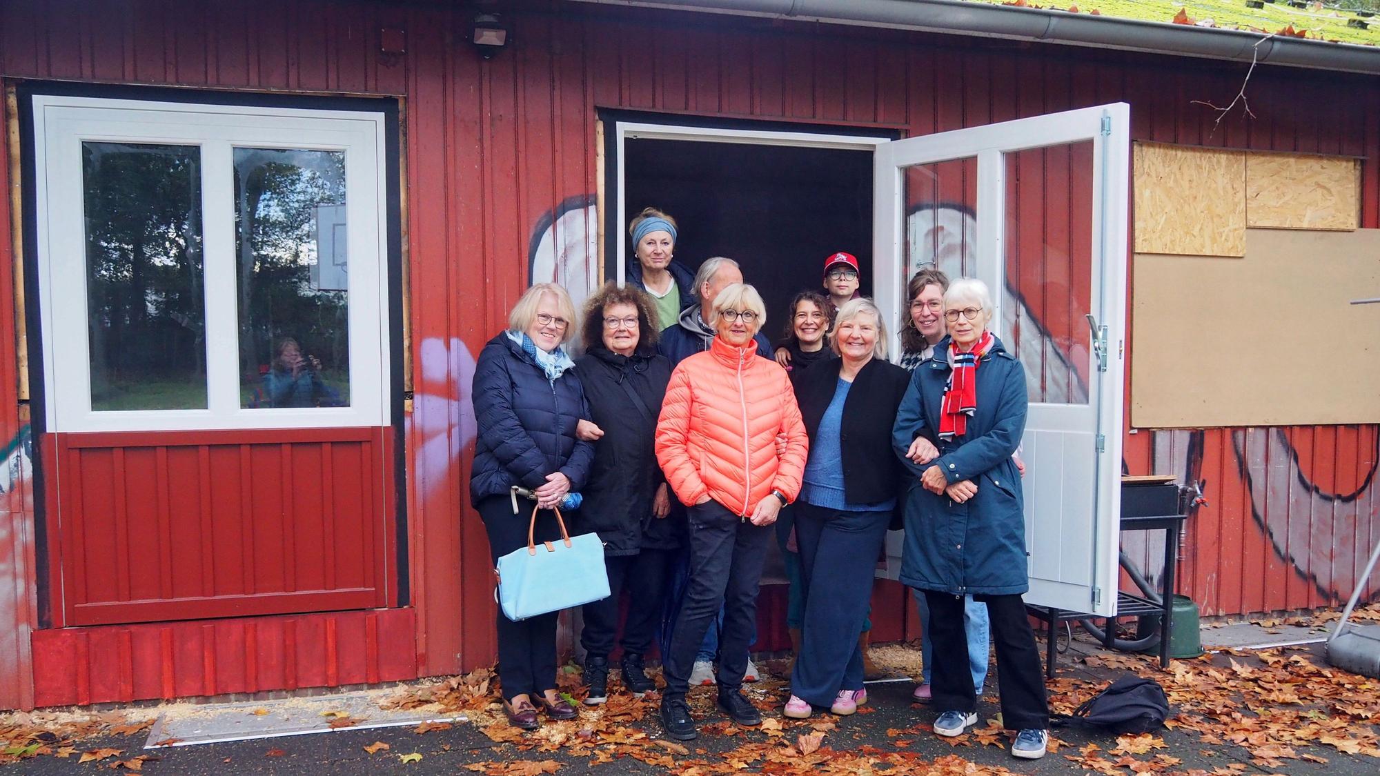 Eine Gruppe Frauen und ein Kind stehen in der Tür eines roten Gebäudes.