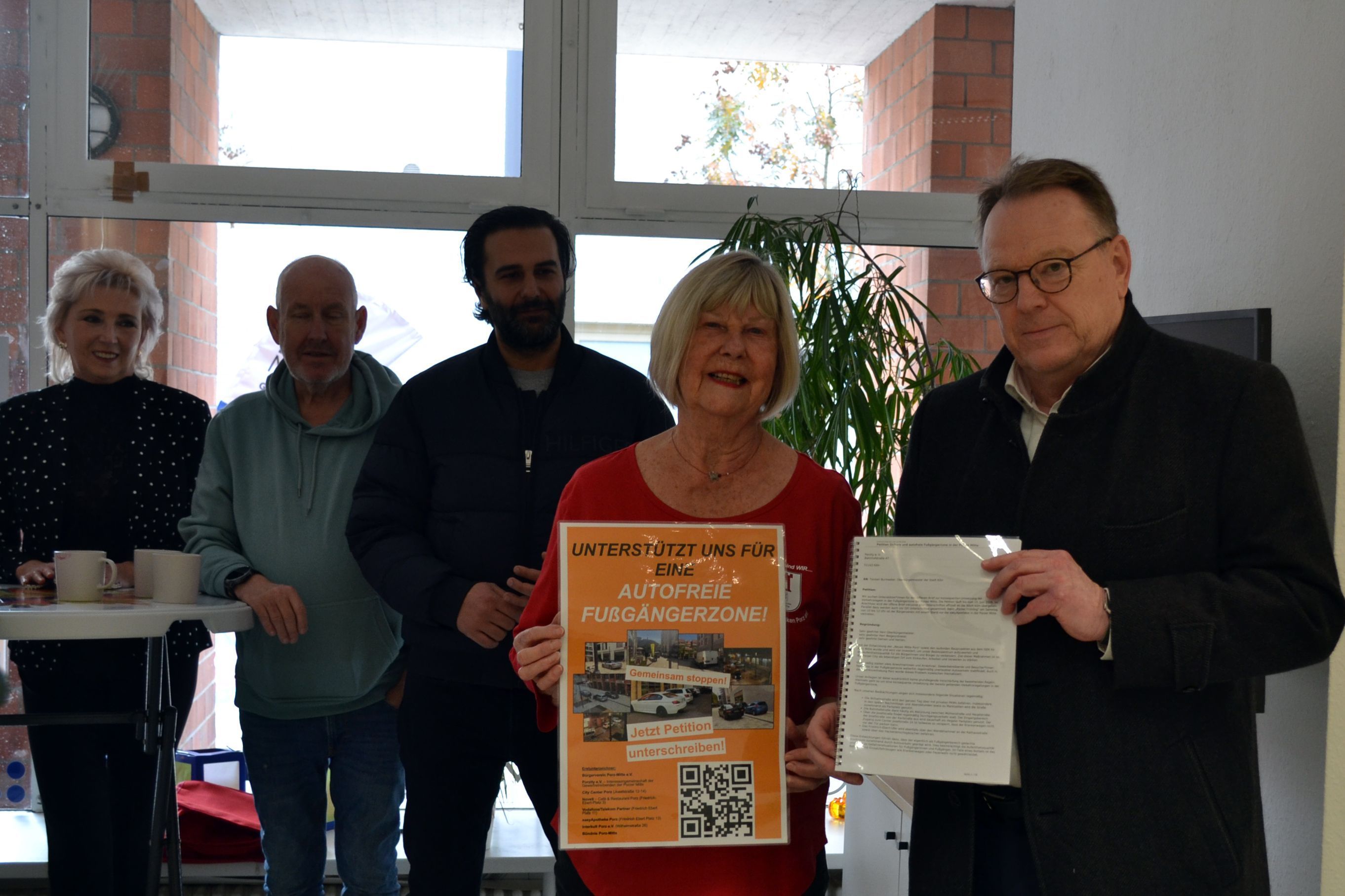 Anita Mirche (2.v.r.) überreicht OB Torsten Burmester (r.) im Beisein von weiteren Initiatoren die Unterschriftenlisten der Petition für eine autofreie Fußgängerzone in der Porzer Innenstadt.