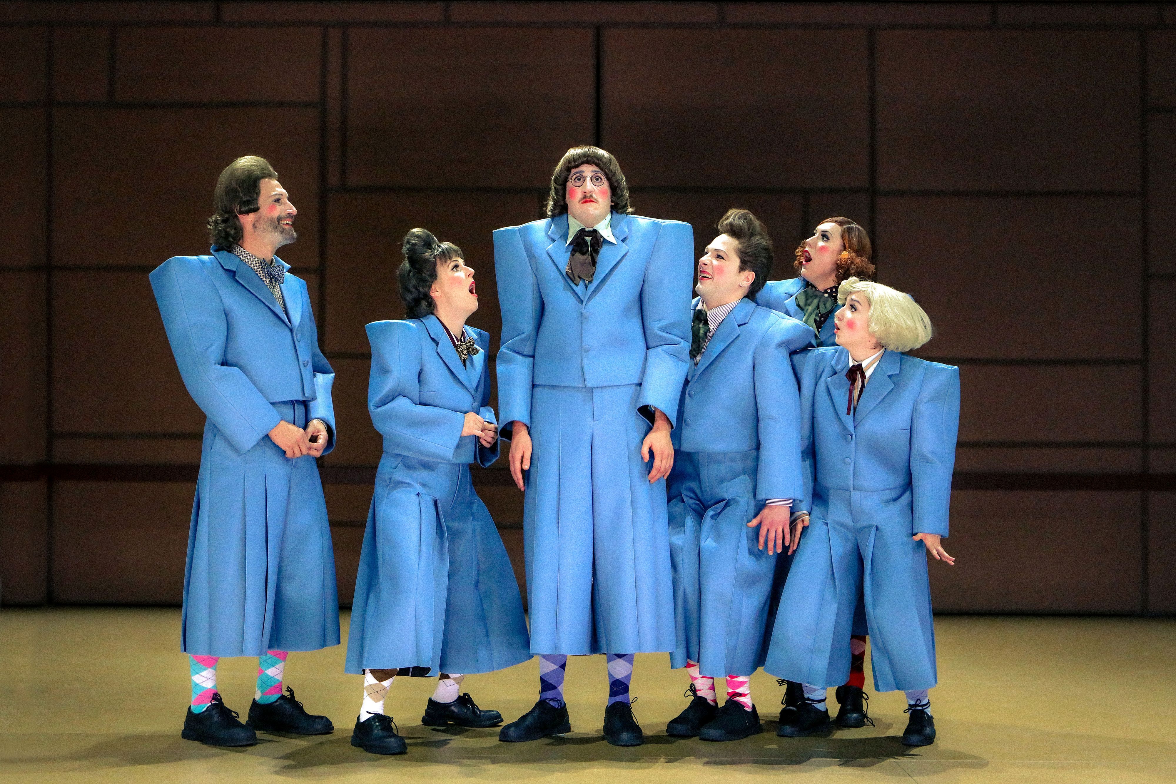 Sechs Schauspieler tragen blaue Anzüge.
