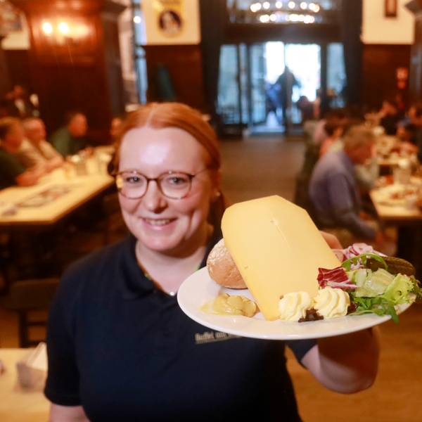Eine Mitarbeiterin im „Gaffel am Dom“ präsentiert den Brauhaus-Klassiker „Halve Hahn“ mit Röggelchen und einer dicken Scheibe mittelaltem Gouda.