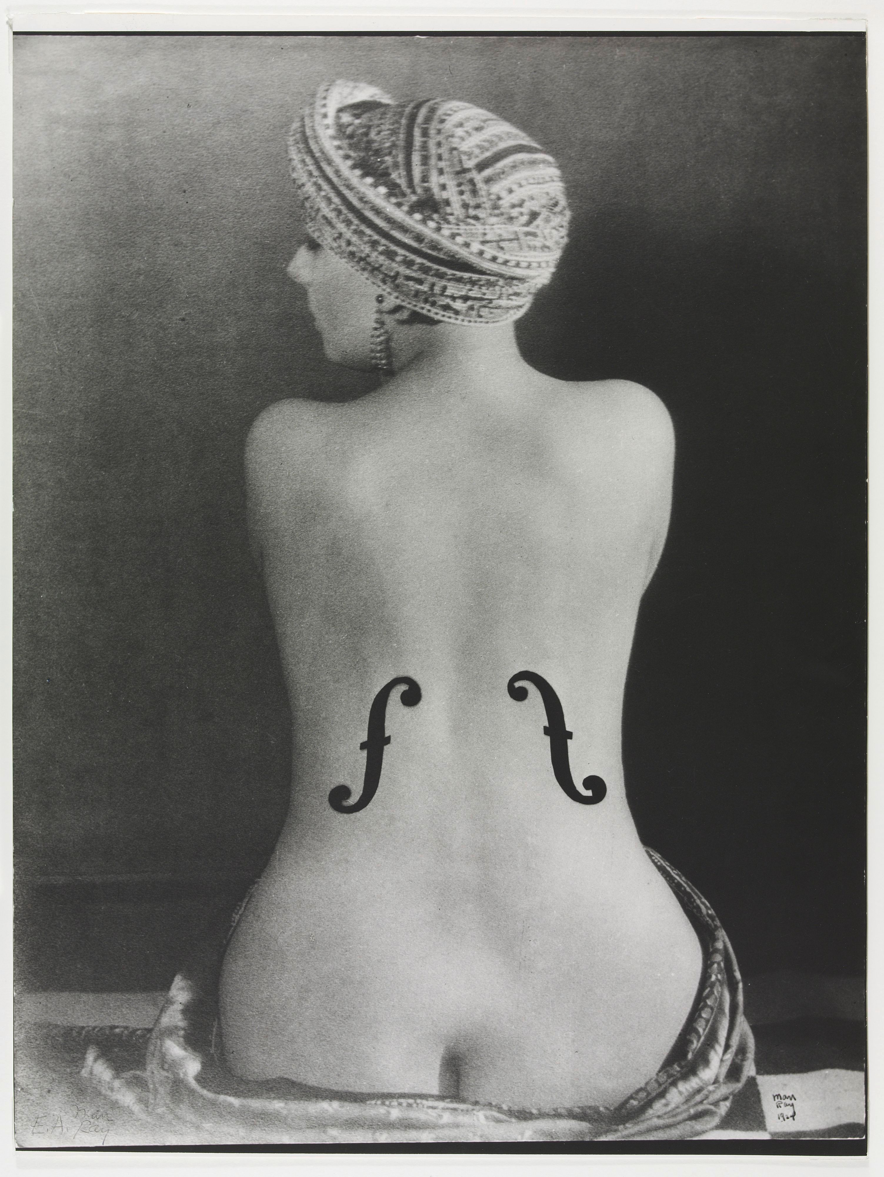 Eine Frau dreht uns den Rücken zu. Sie trägt Schalllöcher wie ein Cello.