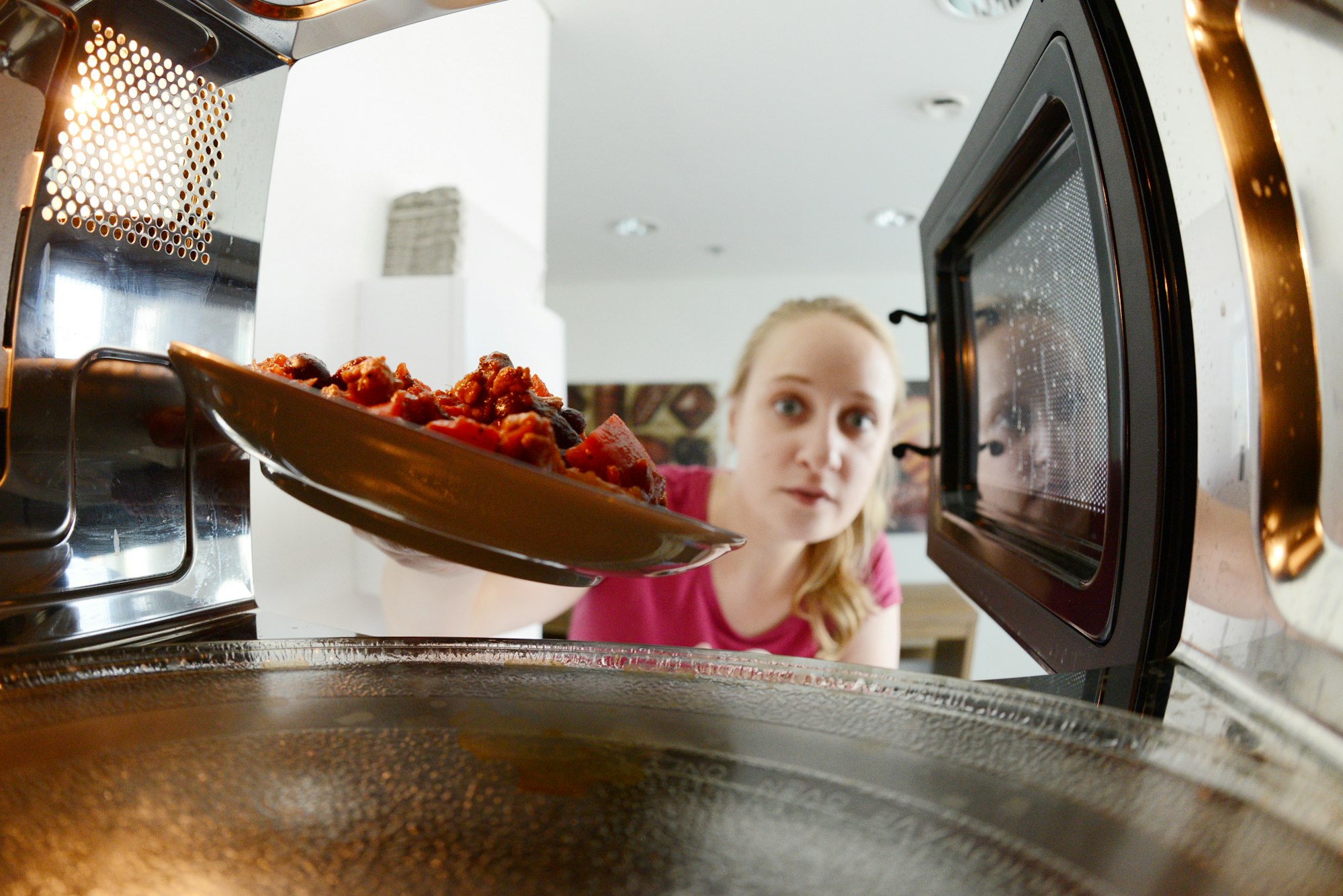 Frau stellt Essen in Mikrowelle