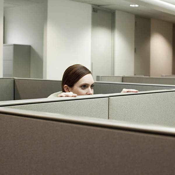 Eine Frau schaut in einem Büro über eine Trennwand.