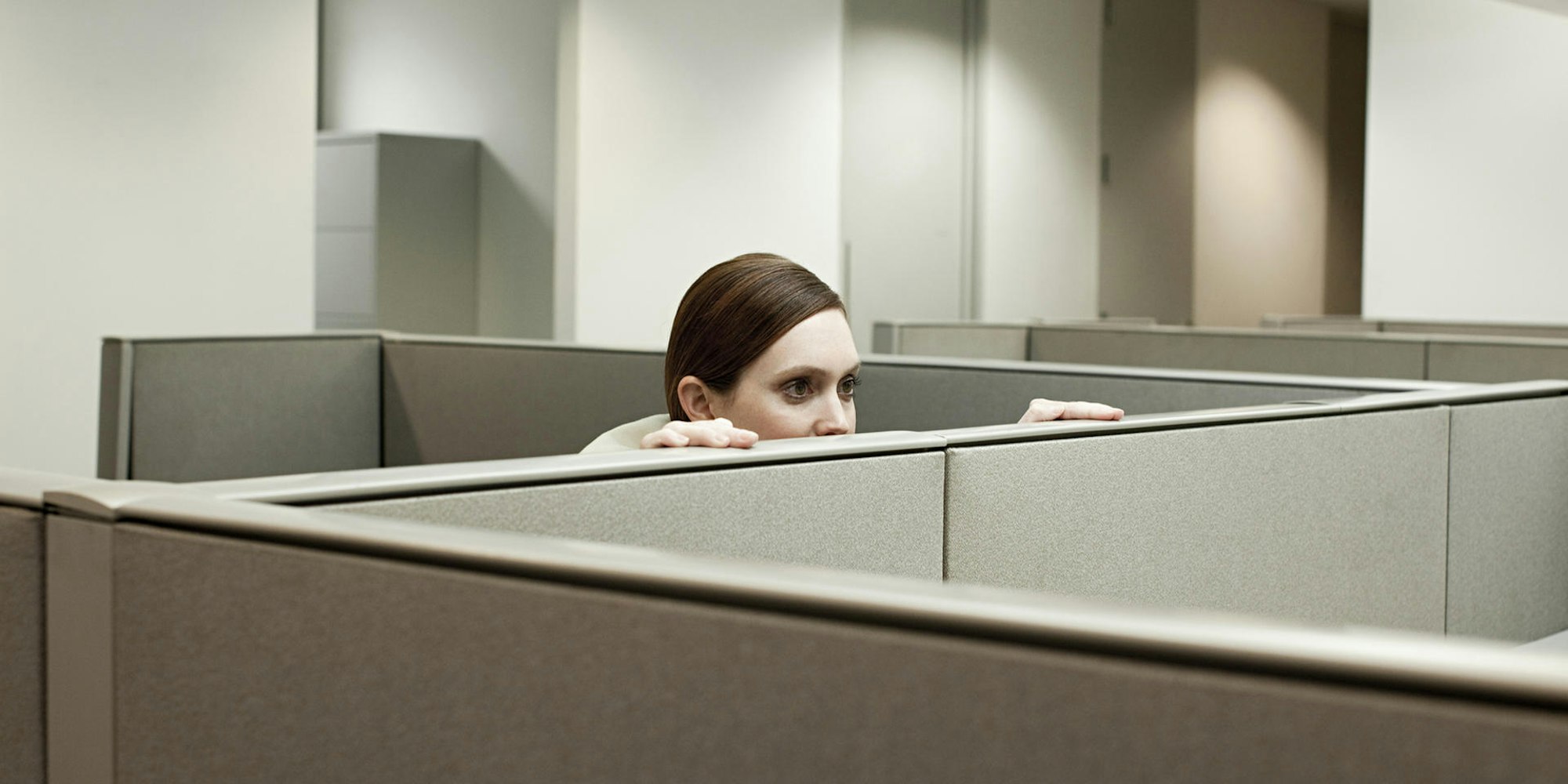 Eine Frau schaut in einem Büro über eine Trennwand.