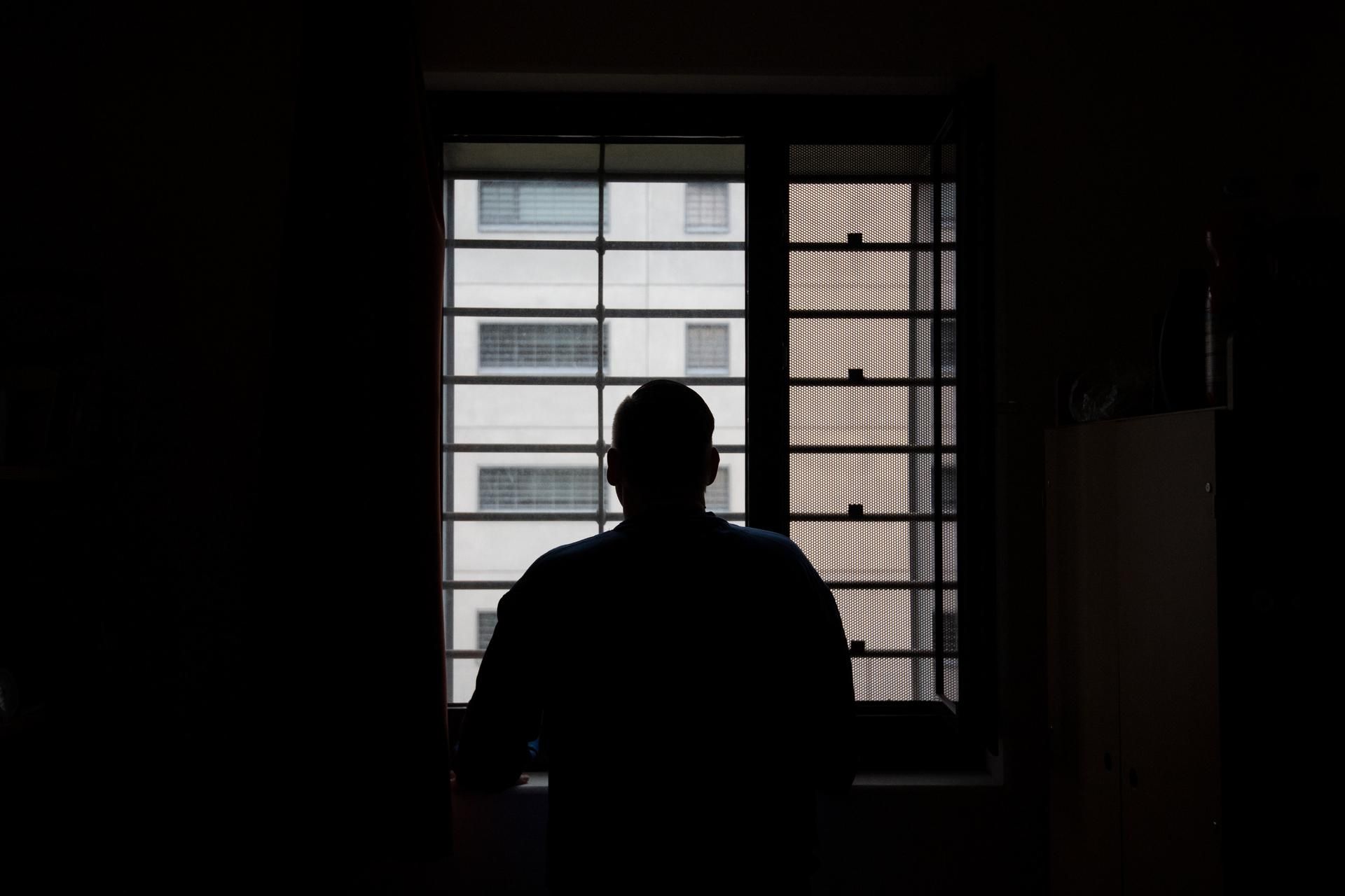 Ein Insasse in einem Gefängnis steht an einem Fenster.
