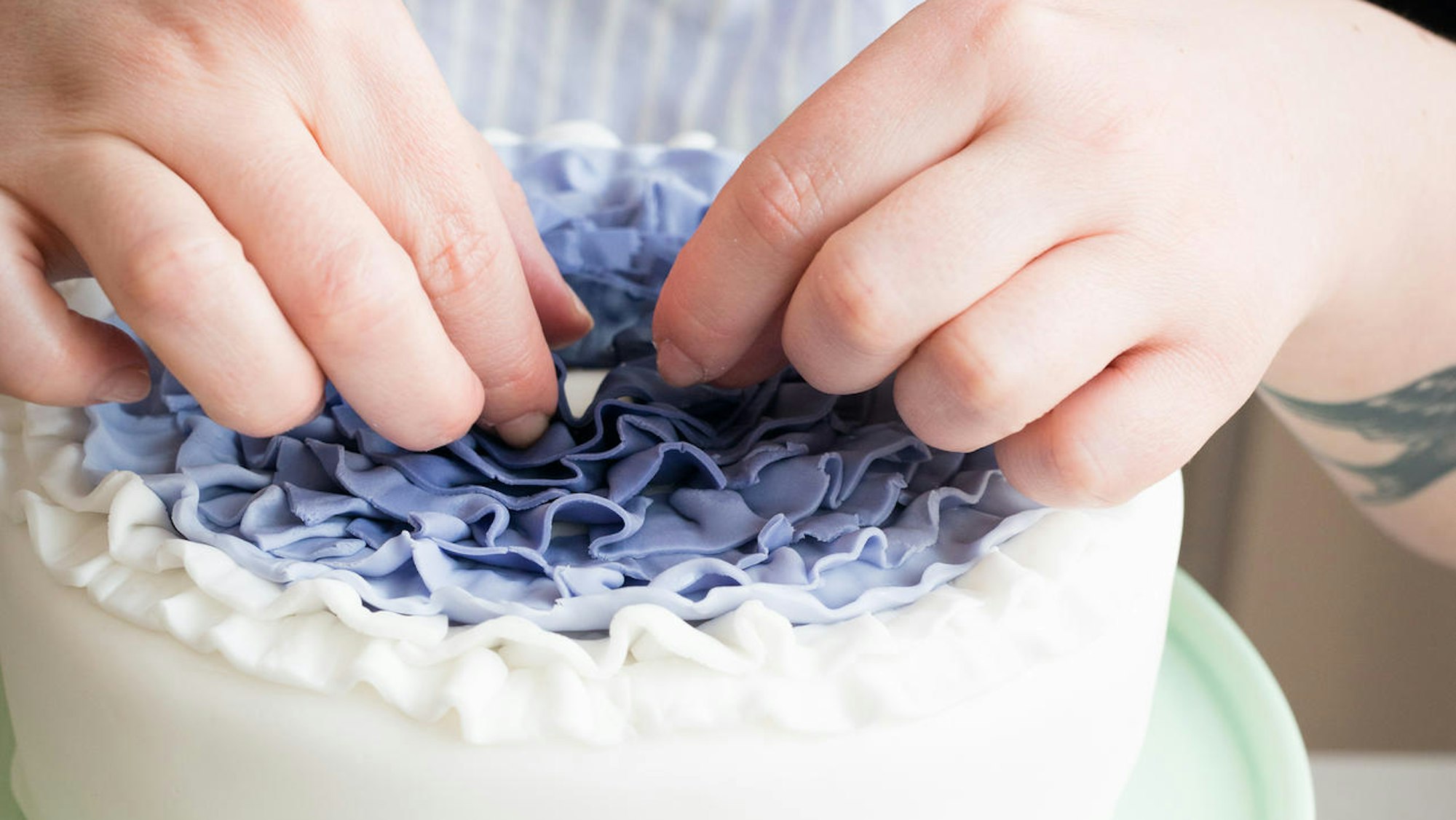 Eine Torte wird mit Fondant-Rüschen verziert.