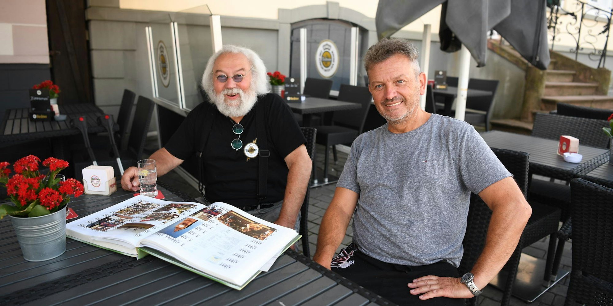 Wirt Jonny und sein Sohn Carsten Johnen sitzen in seinem Lokal an einem Tisch.