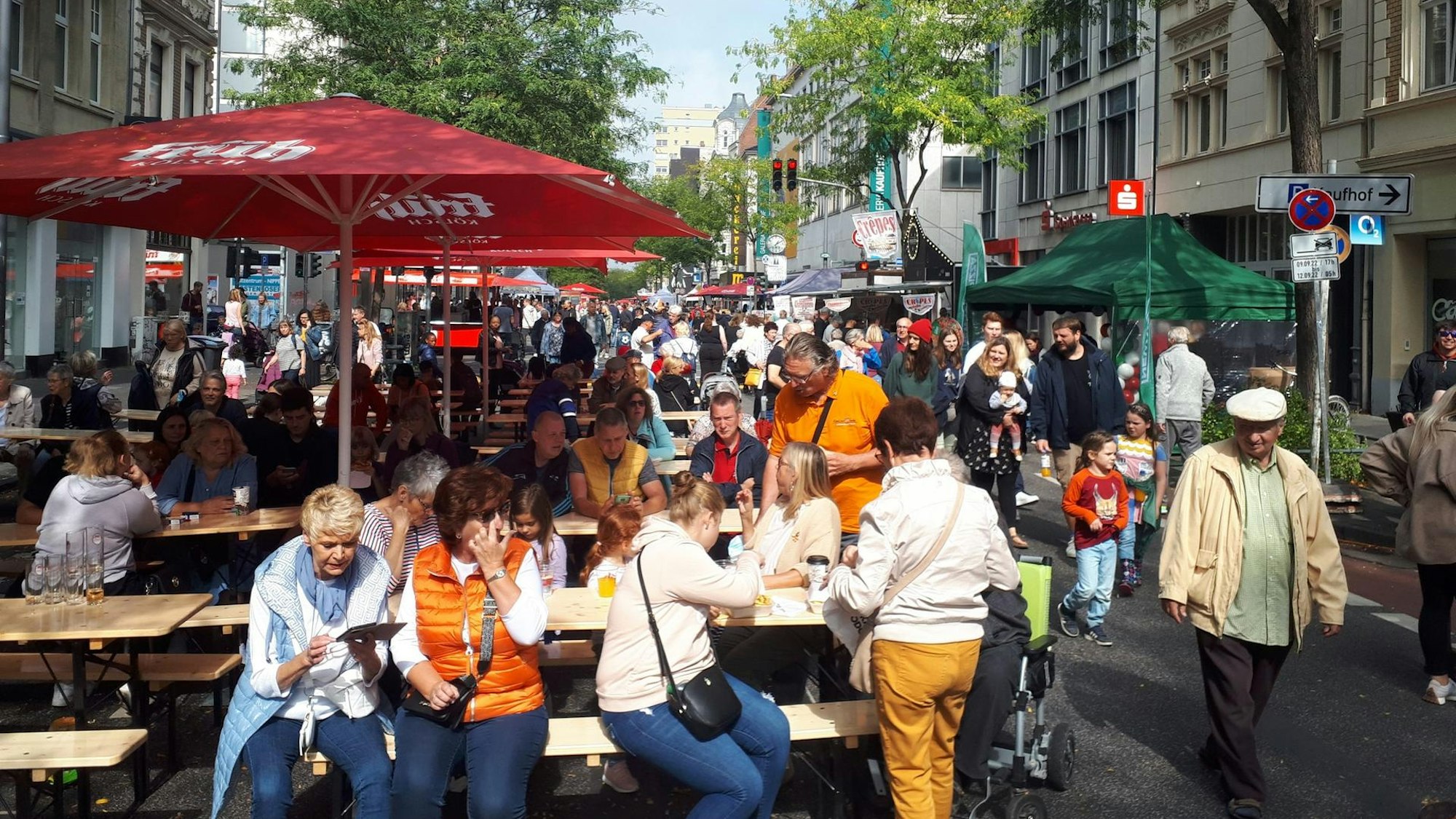 Viele Leute sitzen unter einem Schirm.