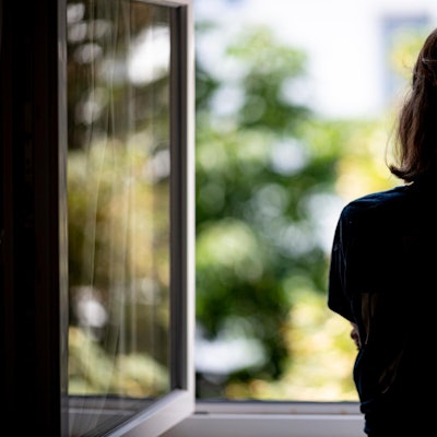 Eine junge Frau schaut aus dem Fenster.