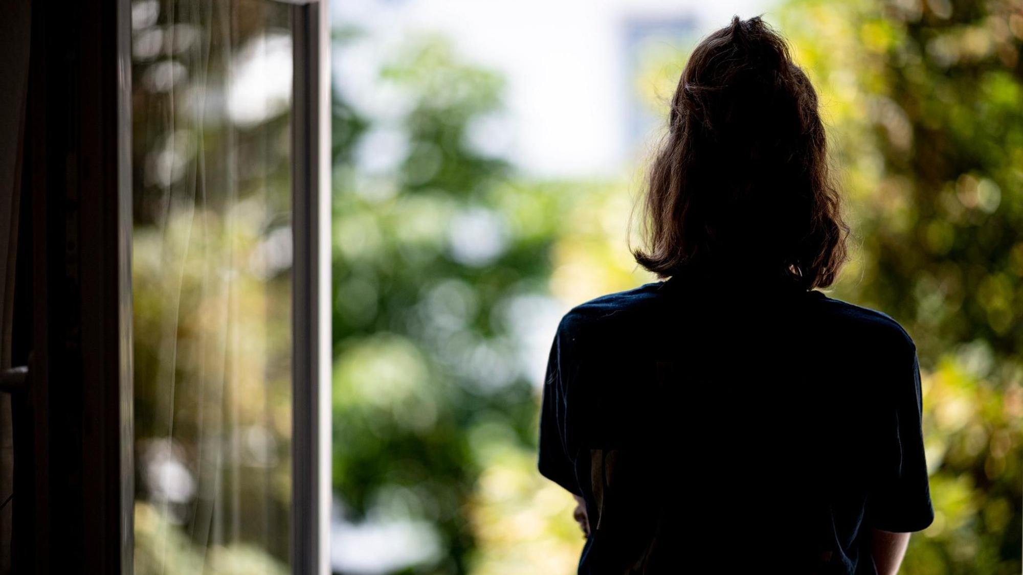 Eine junge Frau schaut aus dem Fenster.