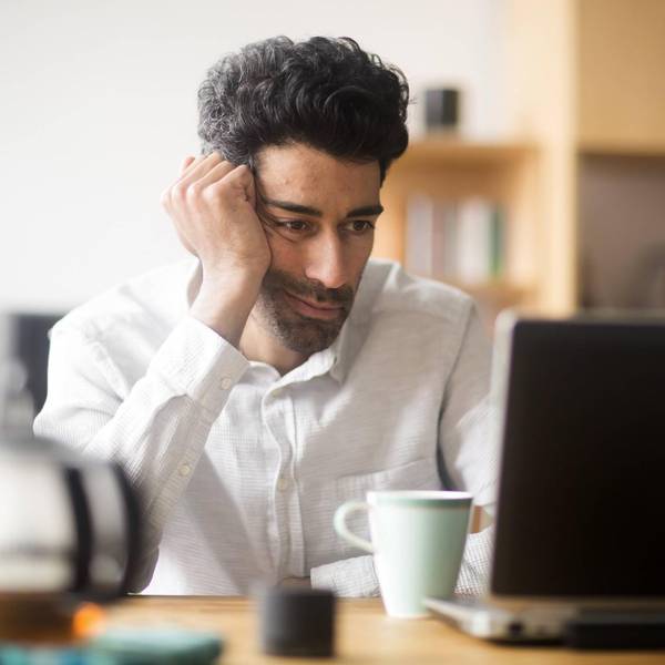 Mann sitzt müde und demotiviert vor seinem Laptop