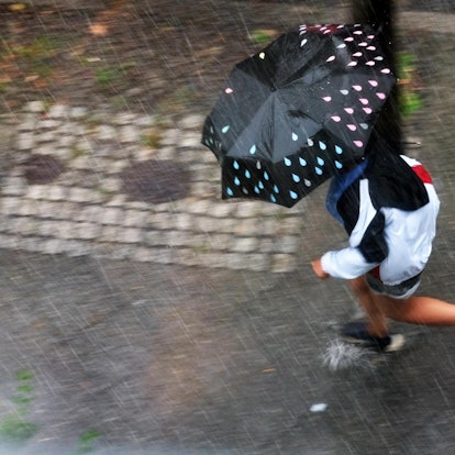 Frau rennt bei einem Sommergewitter mit Schirm herum