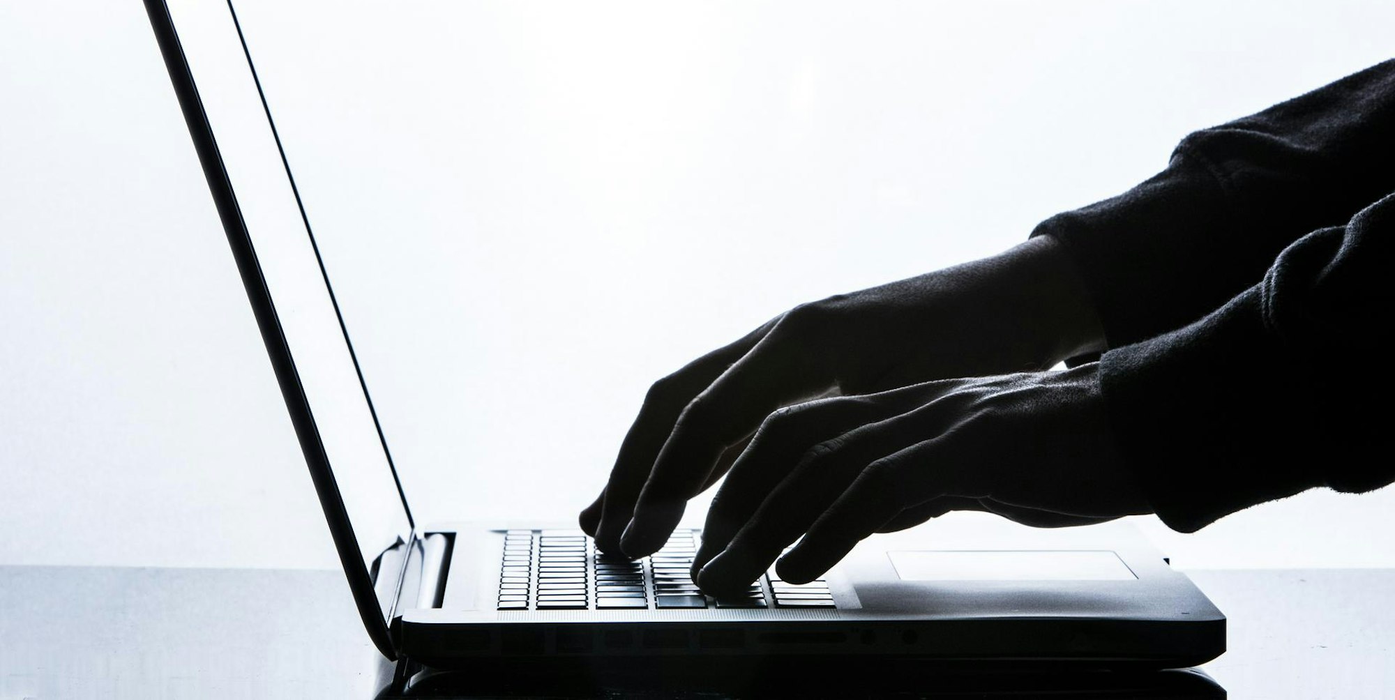 Mann tippt auf Rechner schwarz weiß