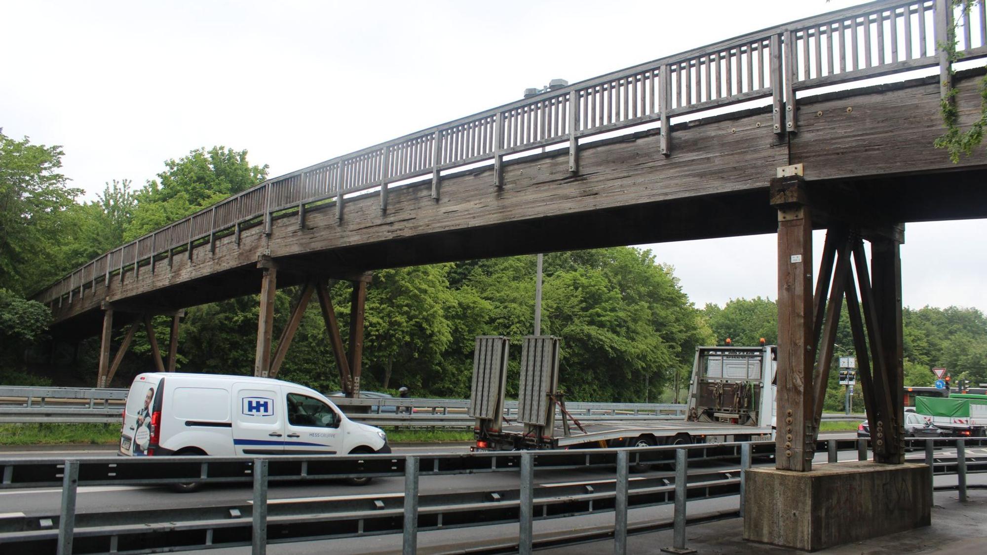 Eine Holzbrücke führt über eine mehrspurige Straße.