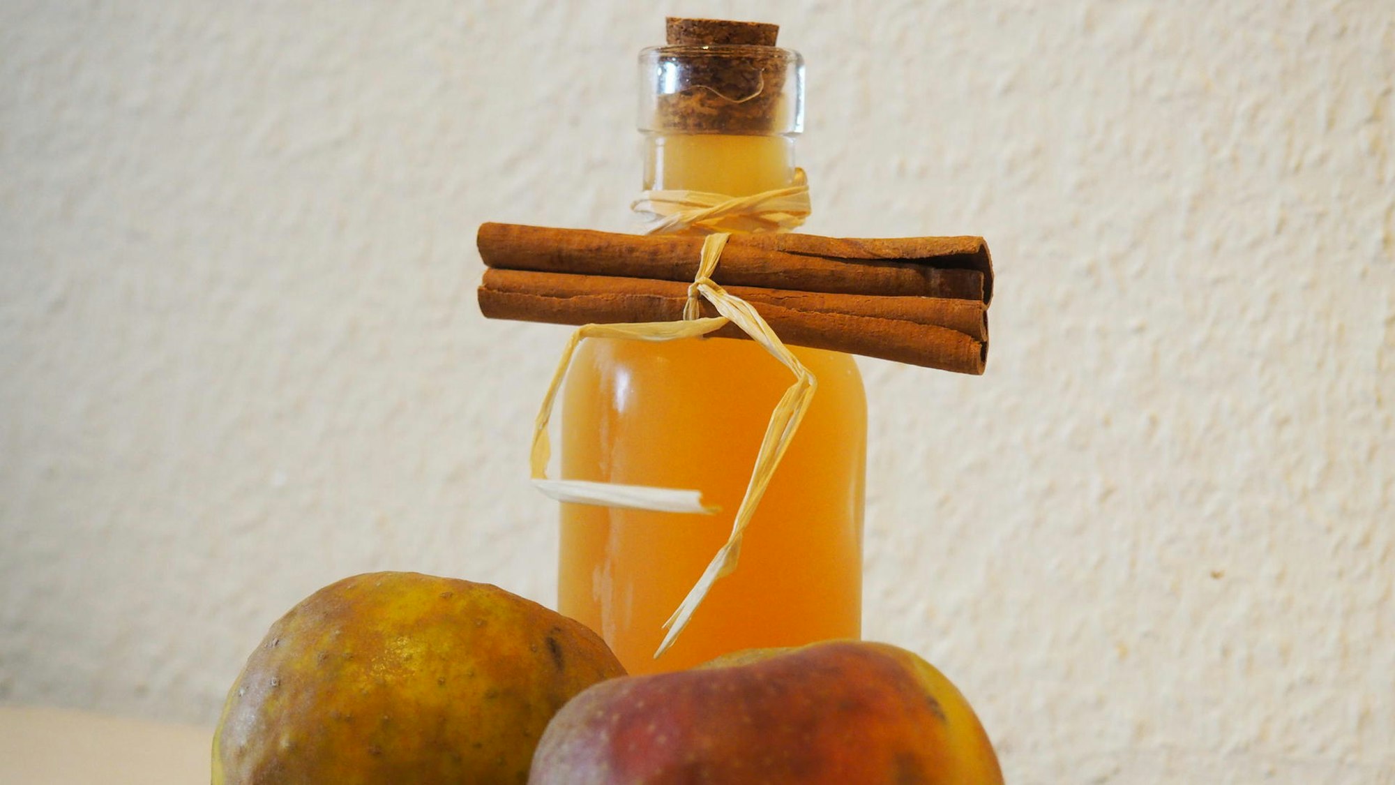 Sirup in einer Flasche, Apfel und Stange Zimt