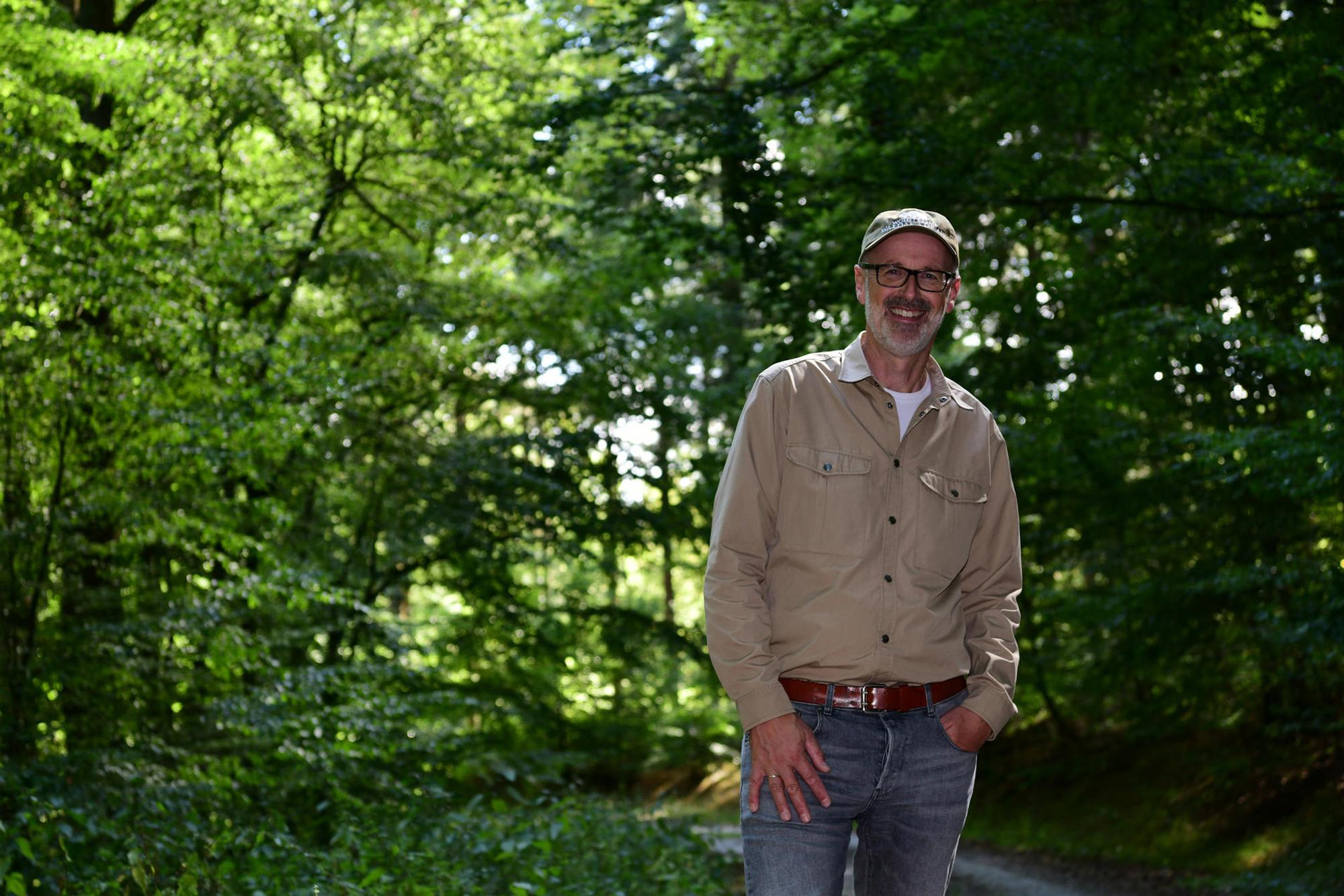 Peter Wohlleben steht vor grünen Bäumen