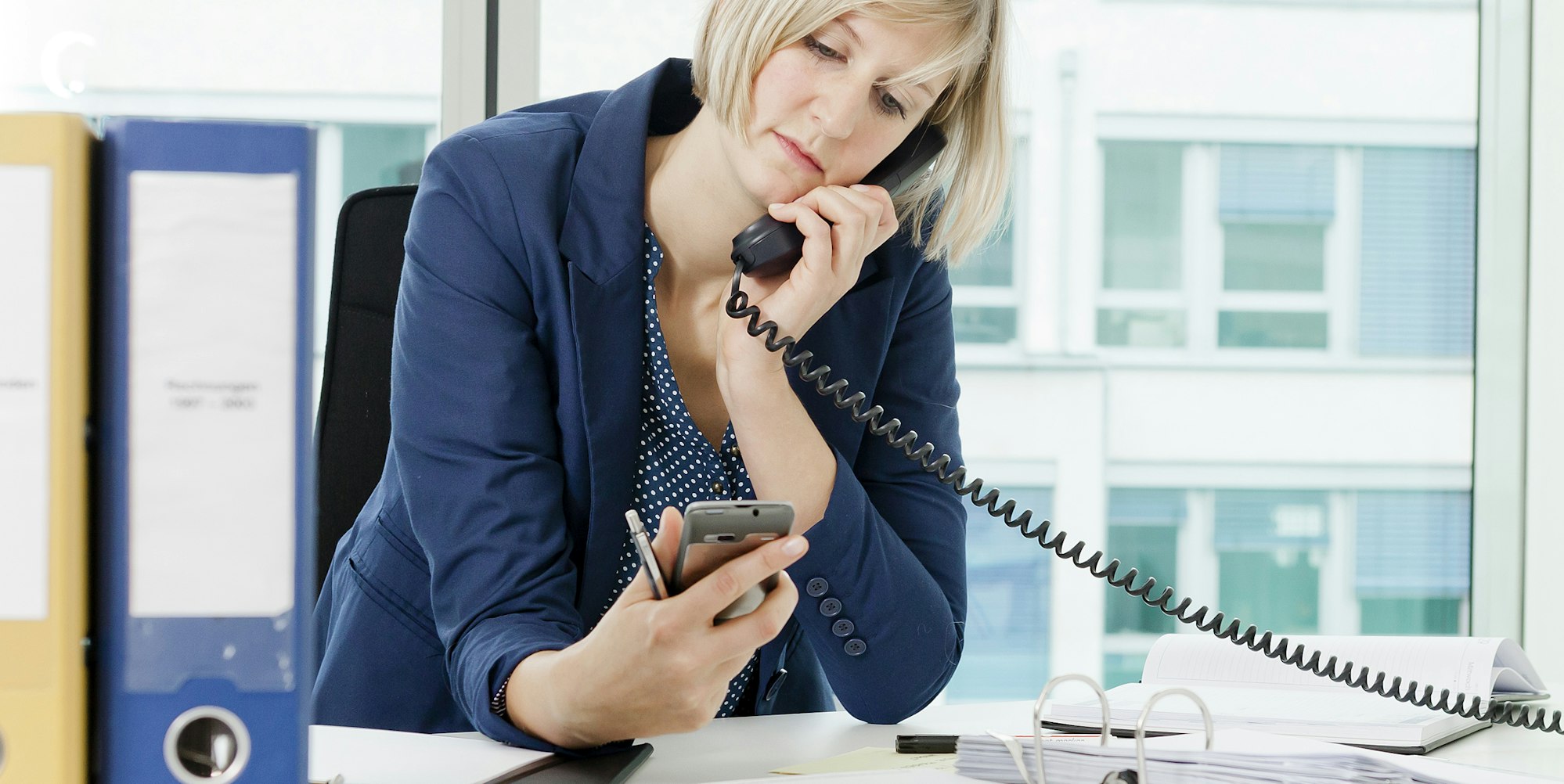 Frau im Büro guckt auf Handy