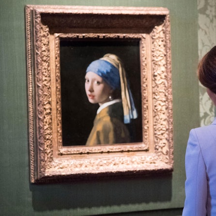 Frau schaut sich „Das Mädchen mit dem Perlenohrring“ an.