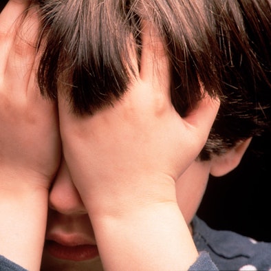 Kind hält sich die Hände vor das Gesicht.