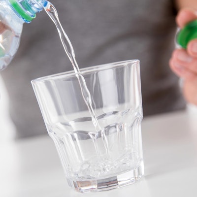 Jemand schüttet sich ein Glas Mineralwasser ein