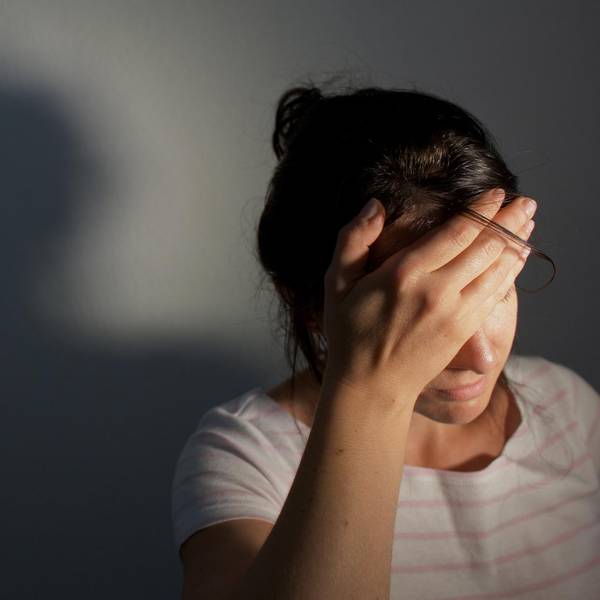 Frau hält sich den Kopf und hat Kopfschmerzen