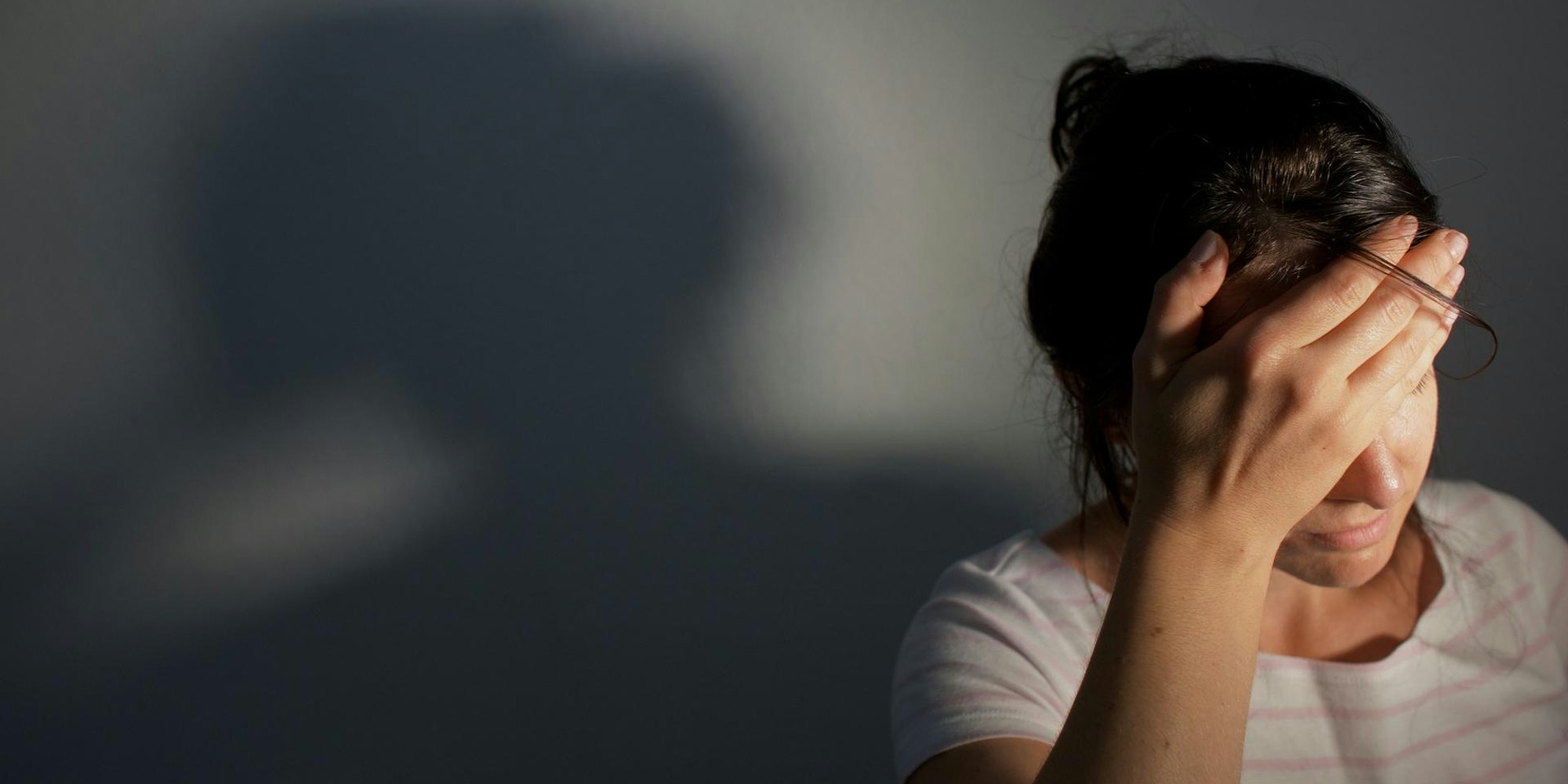 Frau hält sich den Kopf und hat Kopfschmerzen