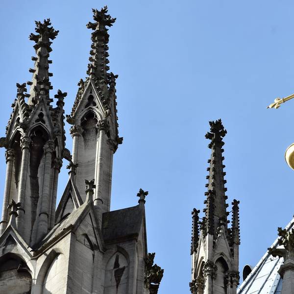 Ein goldenes Kreuz auf dem Kölner Dom leuchtet in der Sonne.
