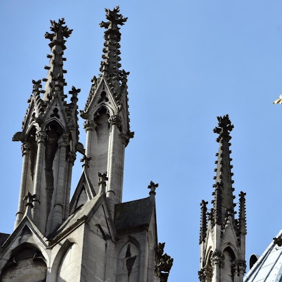 Ein goldenes Kreuz auf dem Kölner Dom leuchtet in der Sonne.