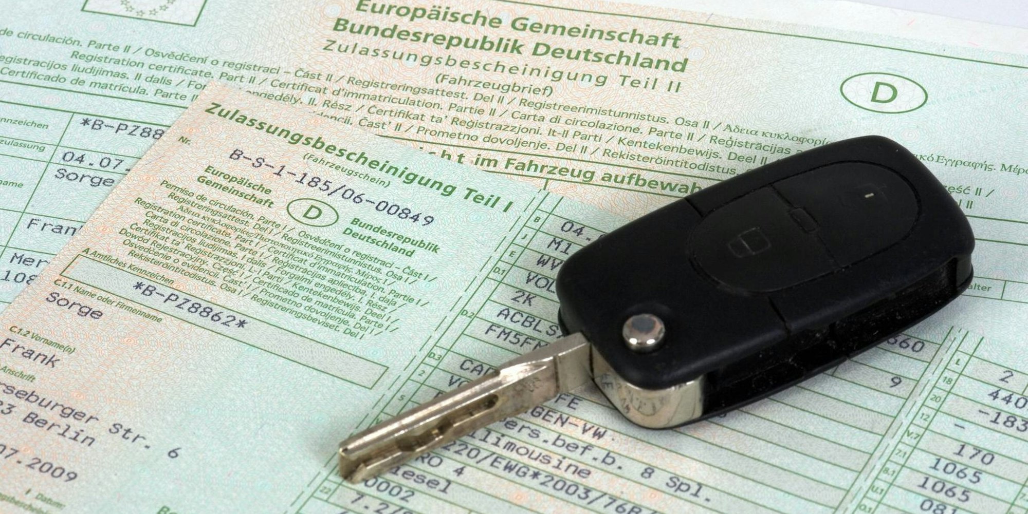 Ein Autoschlüssel liegt auf einem Fahrzeugschein