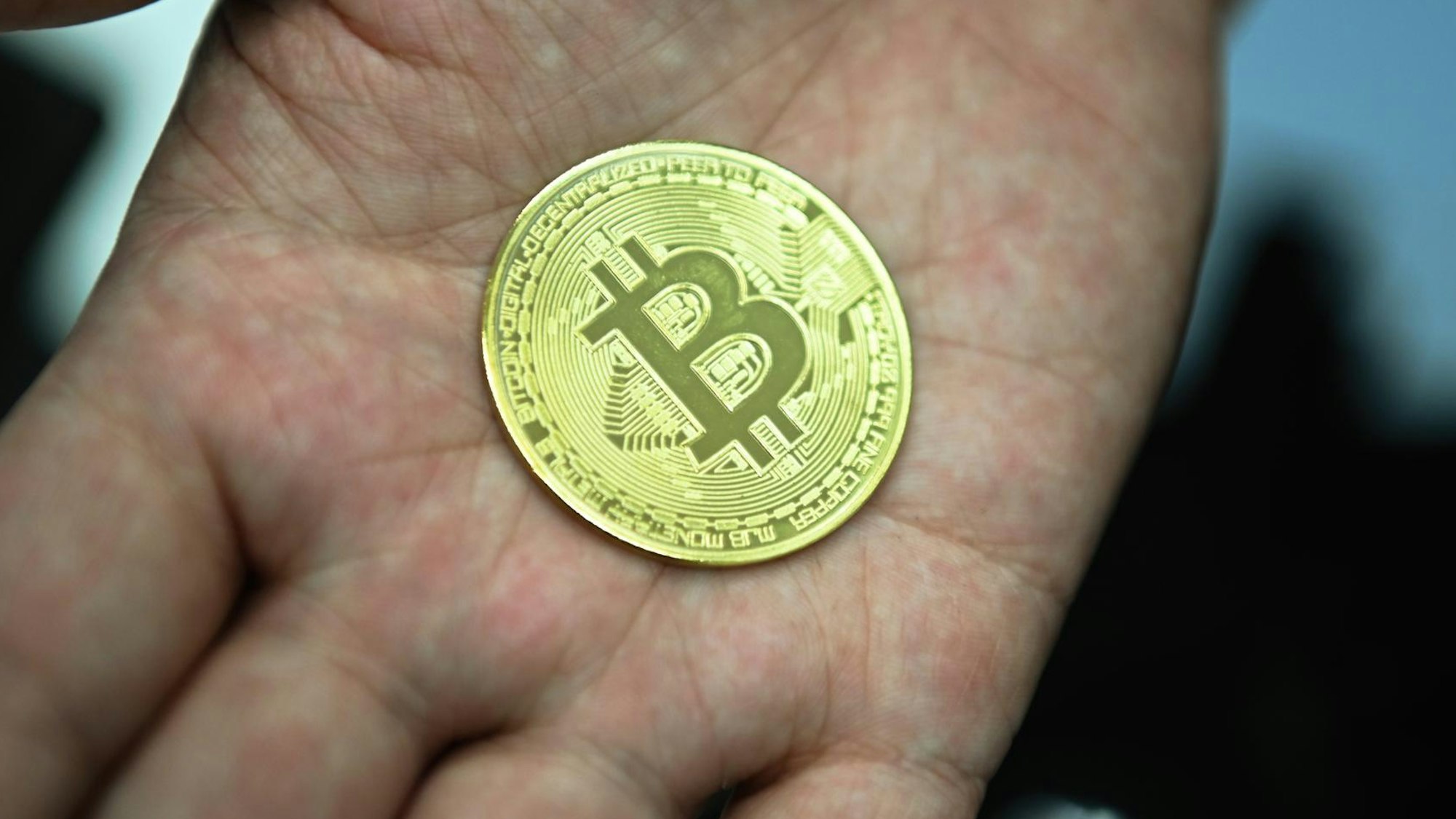 Ein Bitcoin liegt in einer Hand