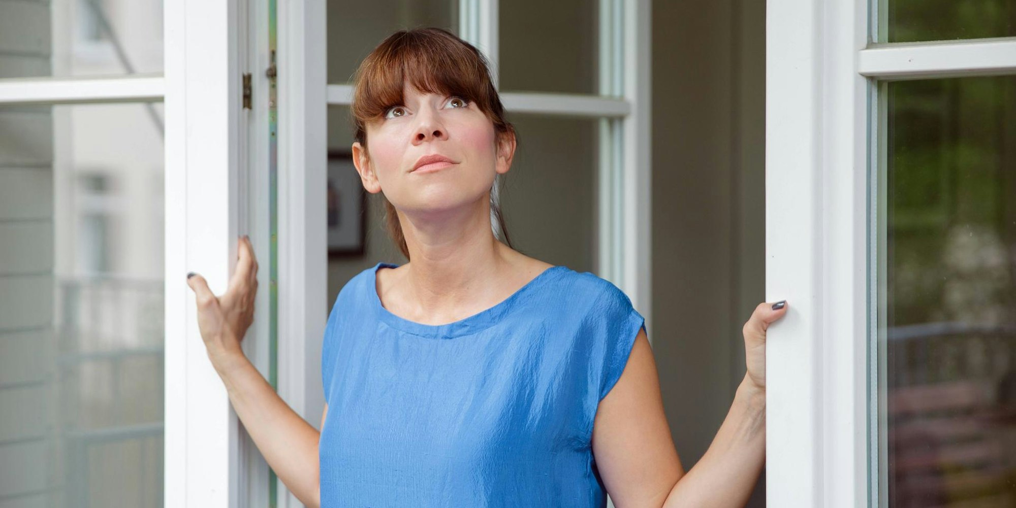 frau guckt aus Terrassentür imago