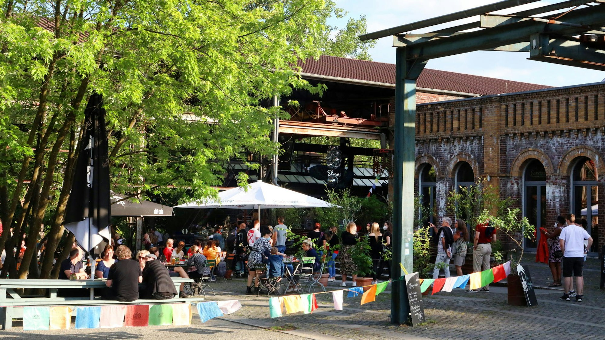 Biergarten mit vielen Menschen und bunten Fahnen