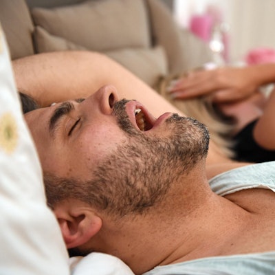 Mann schnarcht, Frau hält sich die Ohren zu