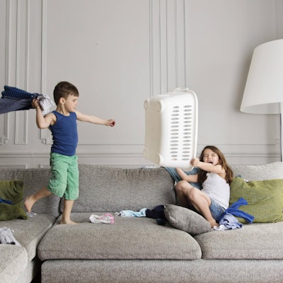 Bruder und Schwester streiten sich auf der Couch.