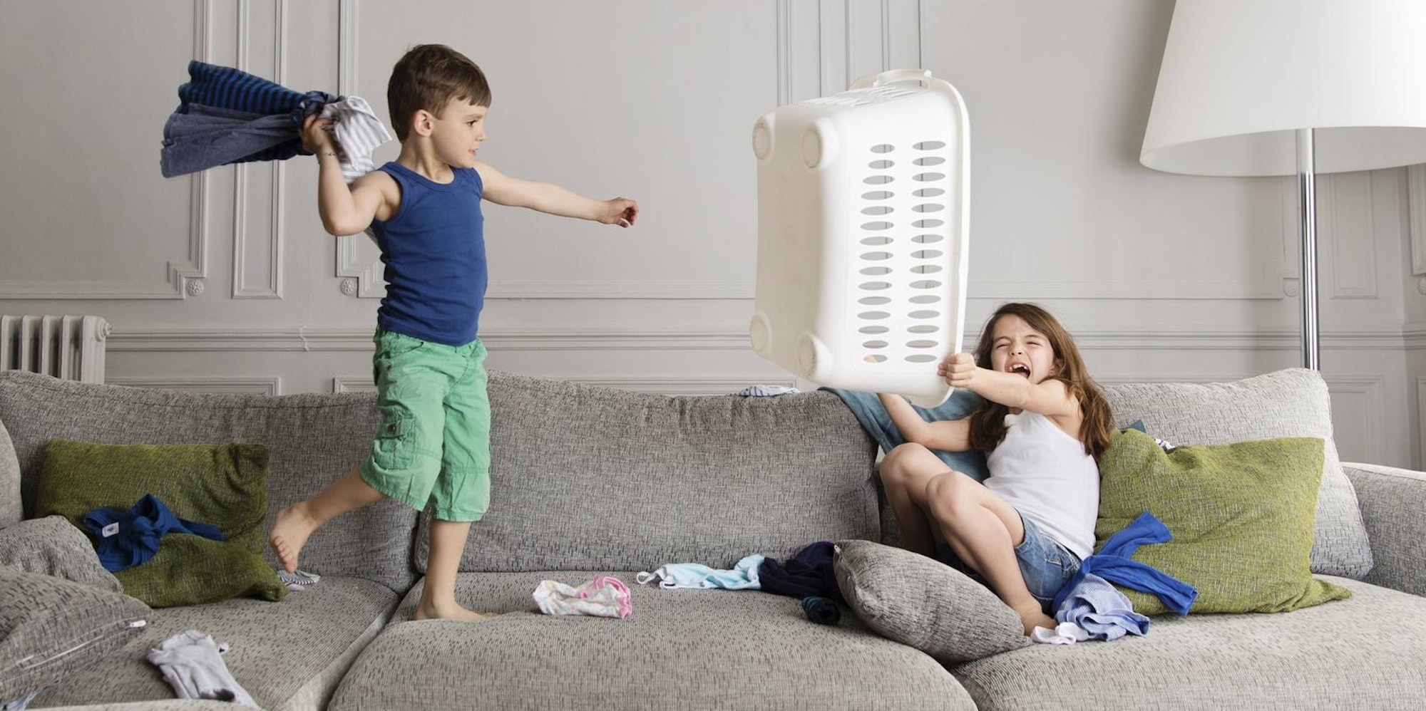 Bruder und Schwester streiten sich auf der Couch.